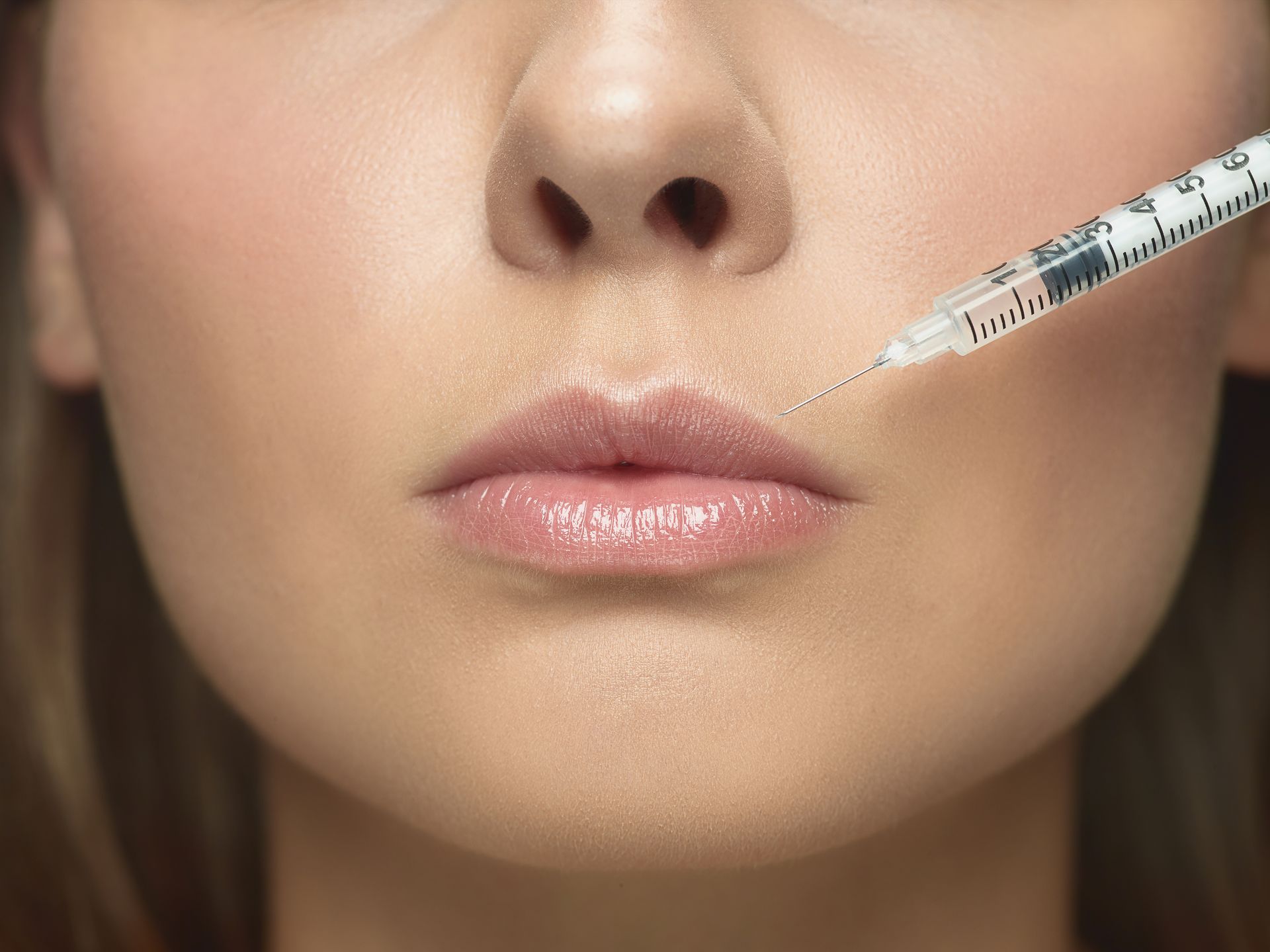 A woman is getting a botox injection in her lips.