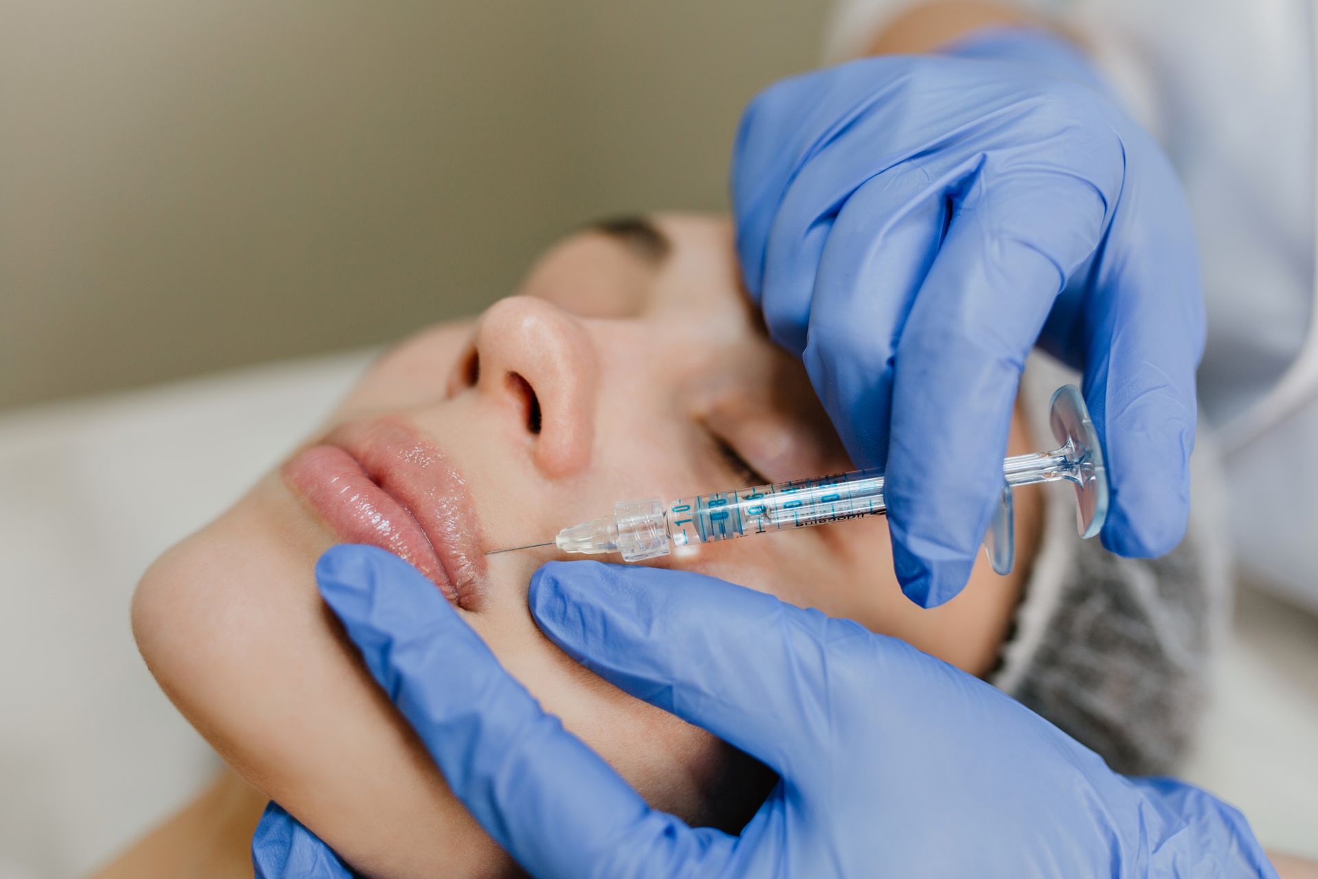 A woman is getting a botox injection in her lips.