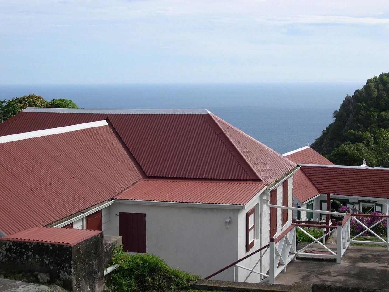 Gray house with gray roof, white trim, and green plants in front.
