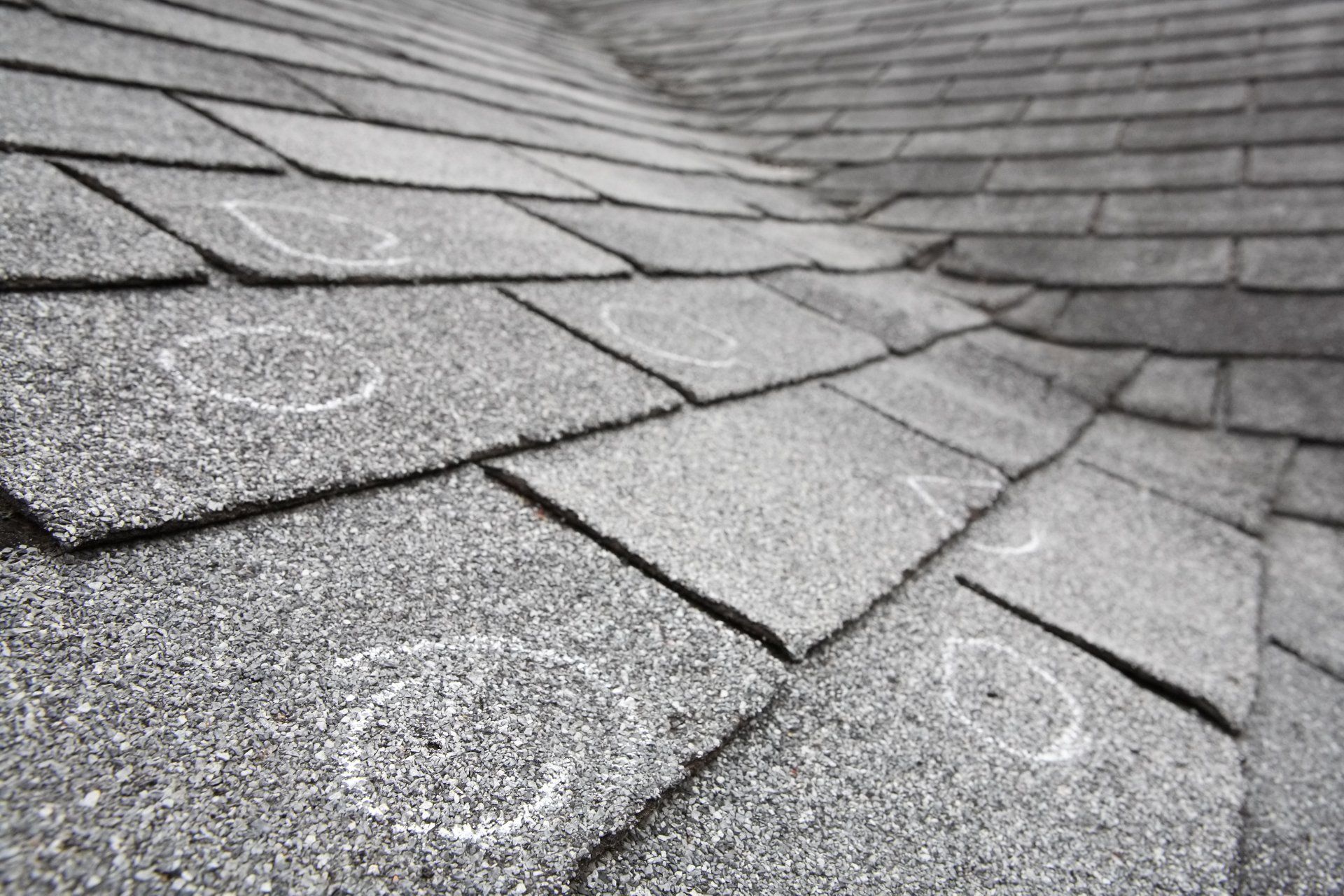 Gray asphalt shingle roof with visible circular hail damage.