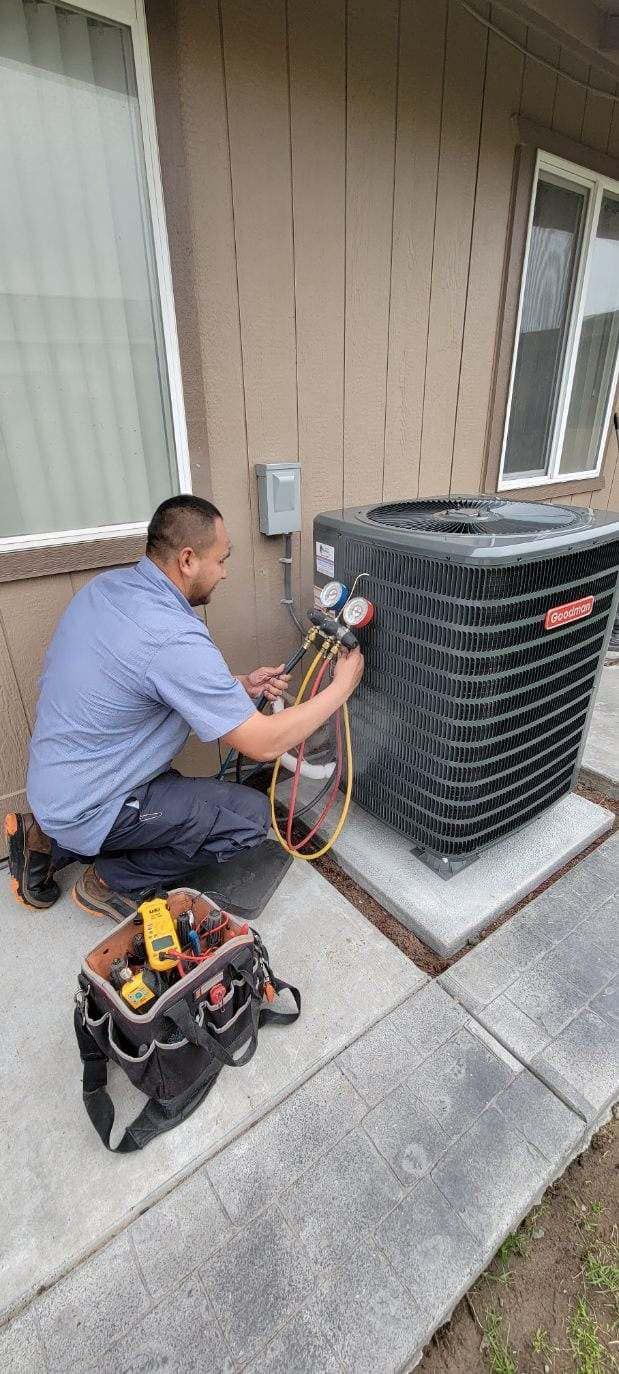 A man is working on an air conditioner outside of a house.