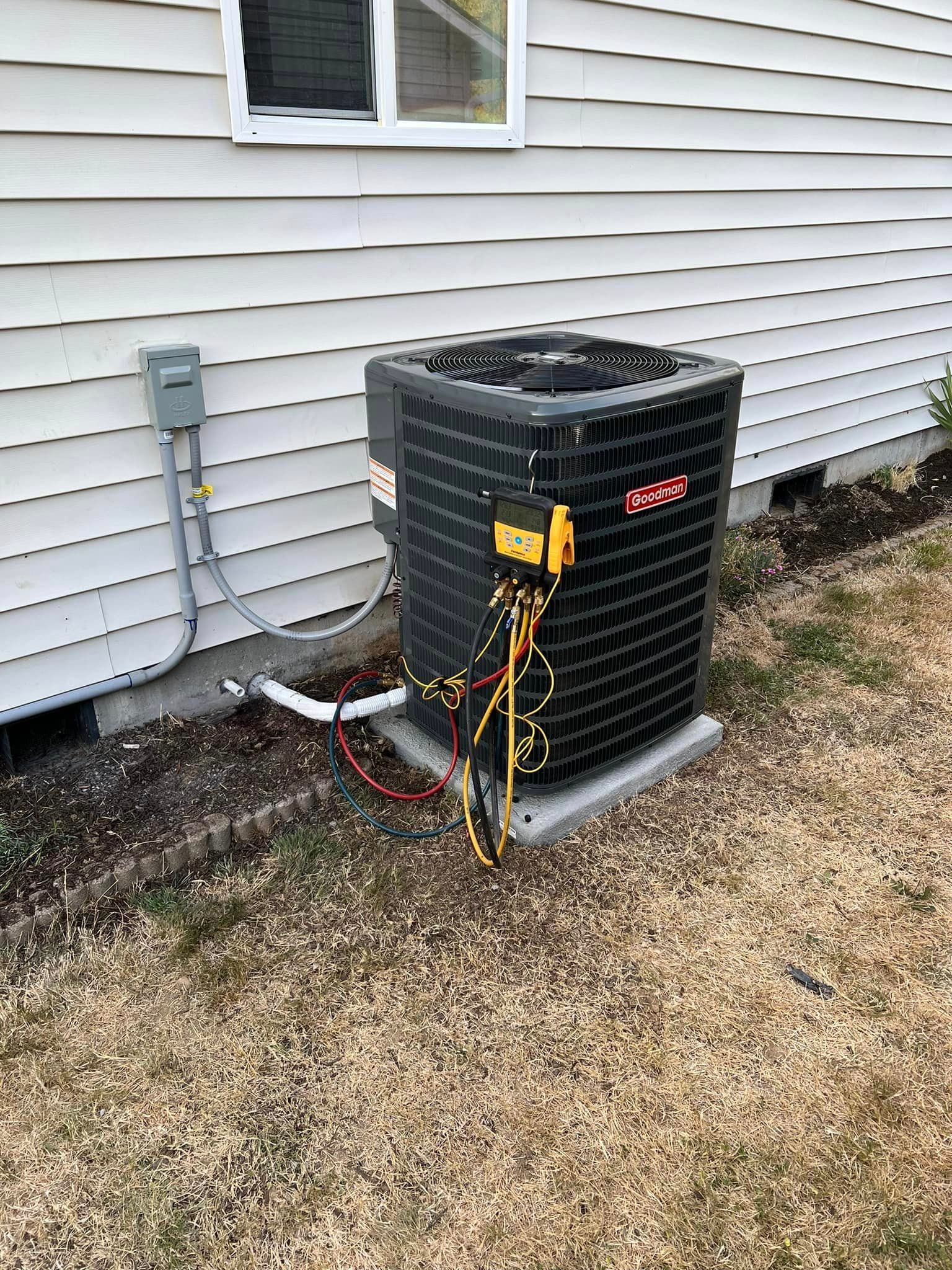 A black air conditioner is sitting on the side of a house.