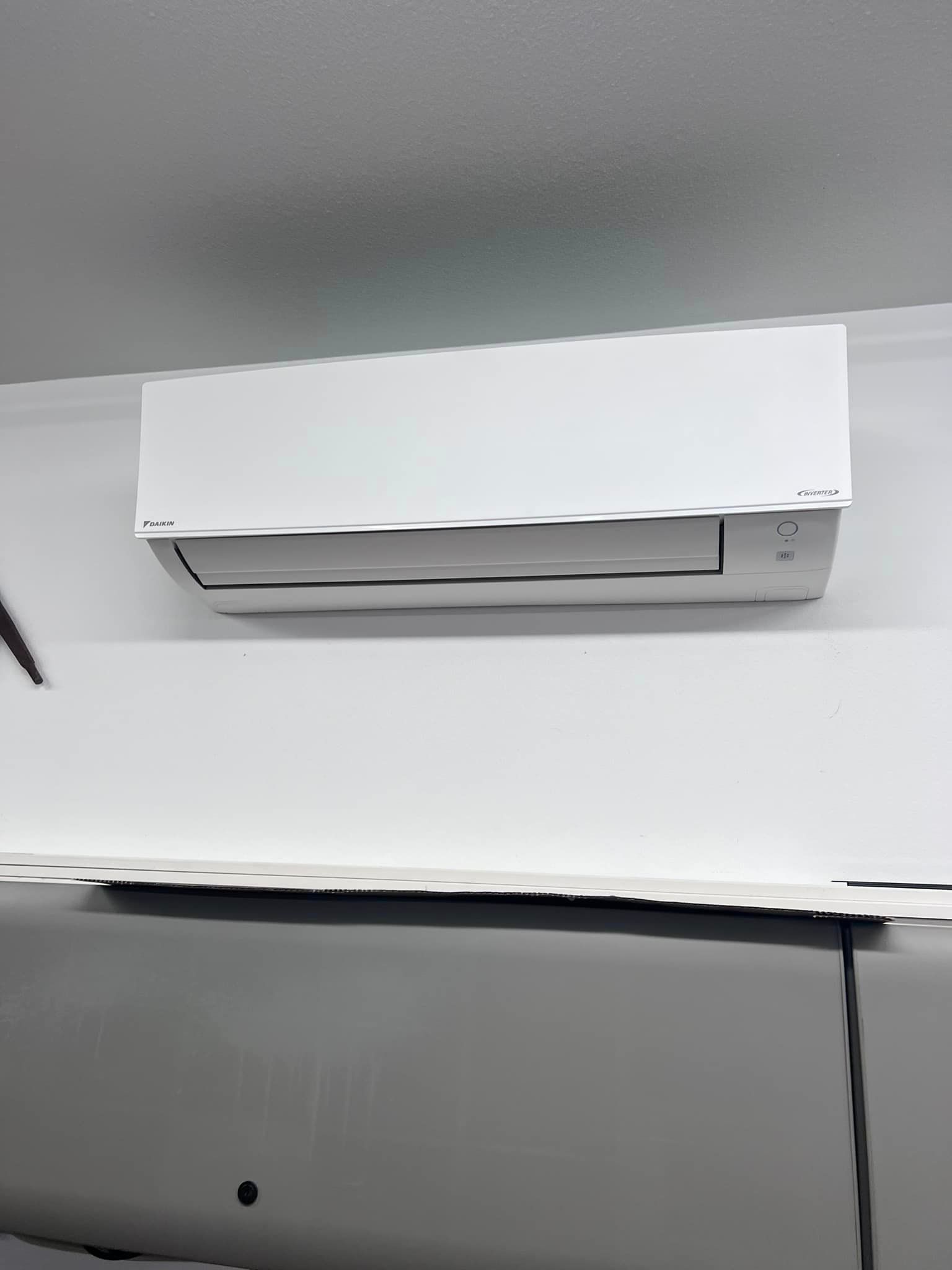 A white air conditioner is hanging from the ceiling in a room.