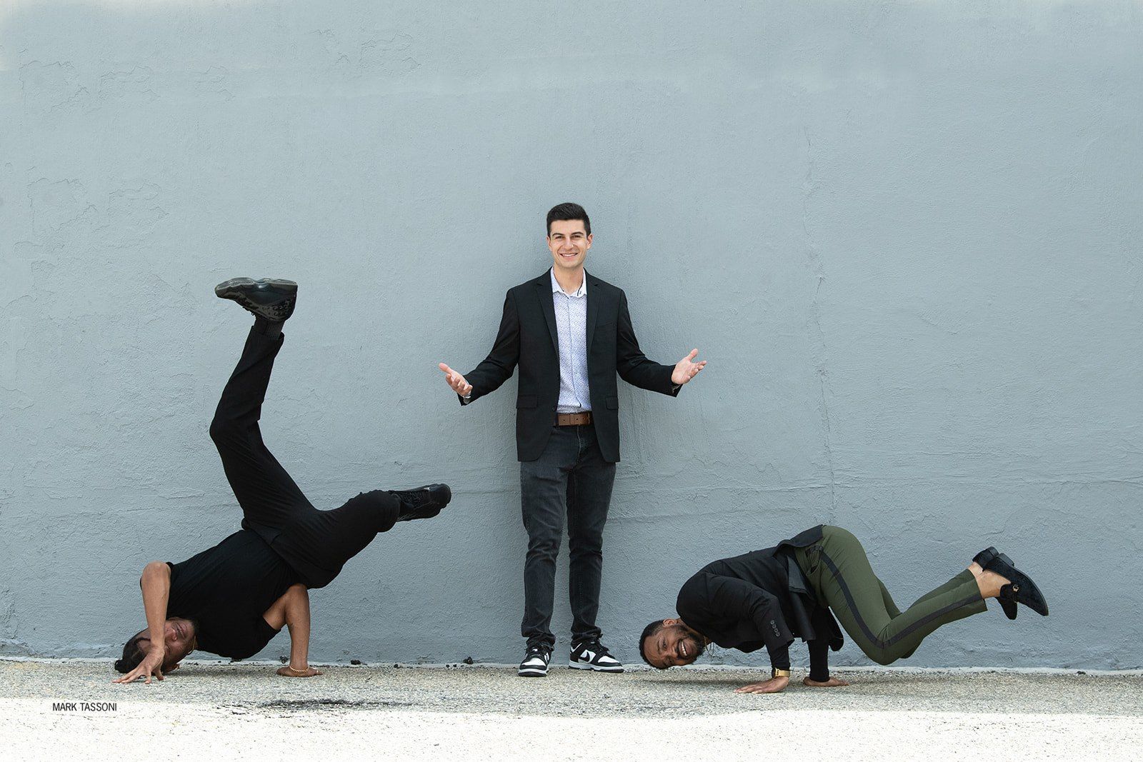 Three men are doing a handstand in front of a wall.