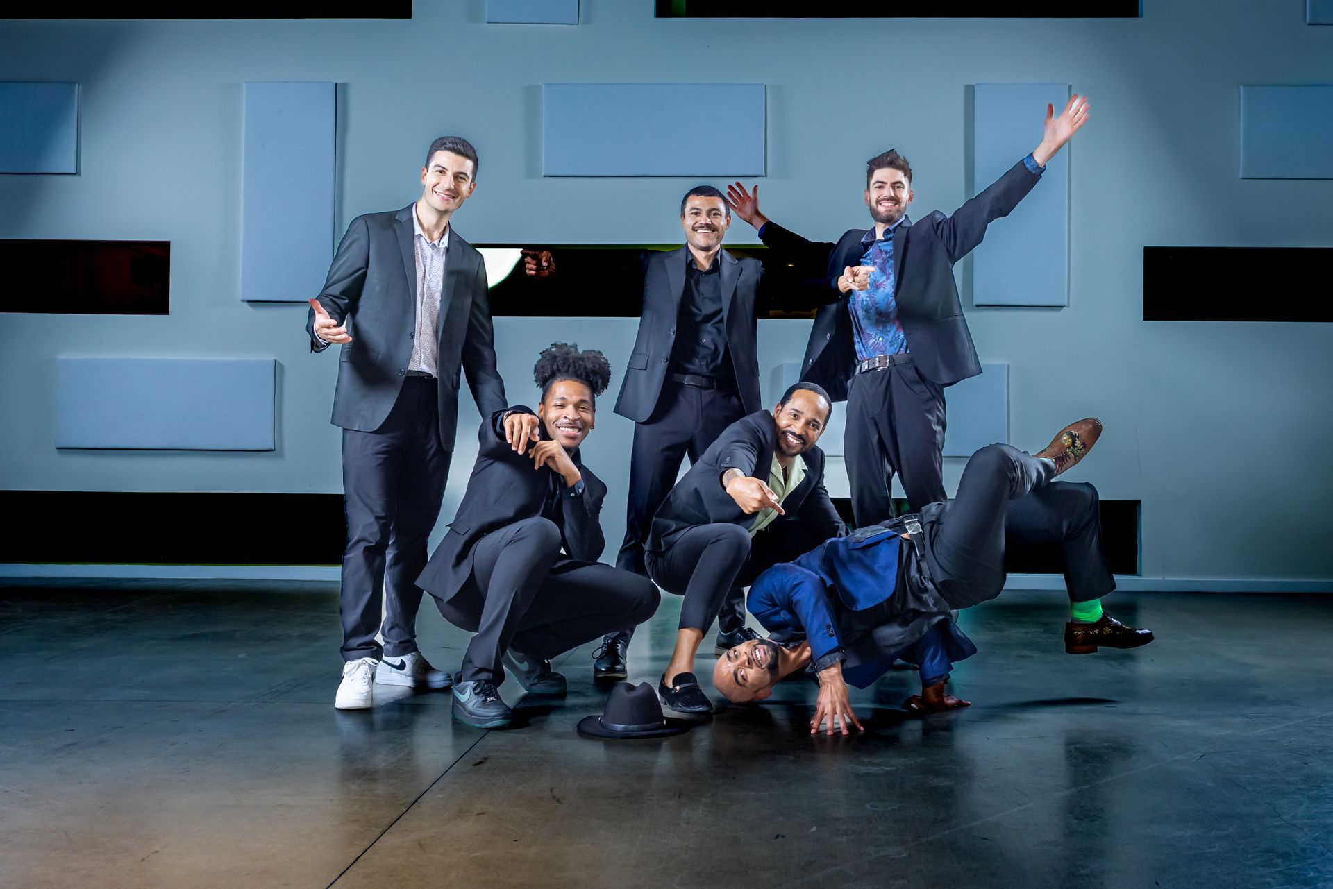 A group of people in suits pose in a studio cheering in the background.
