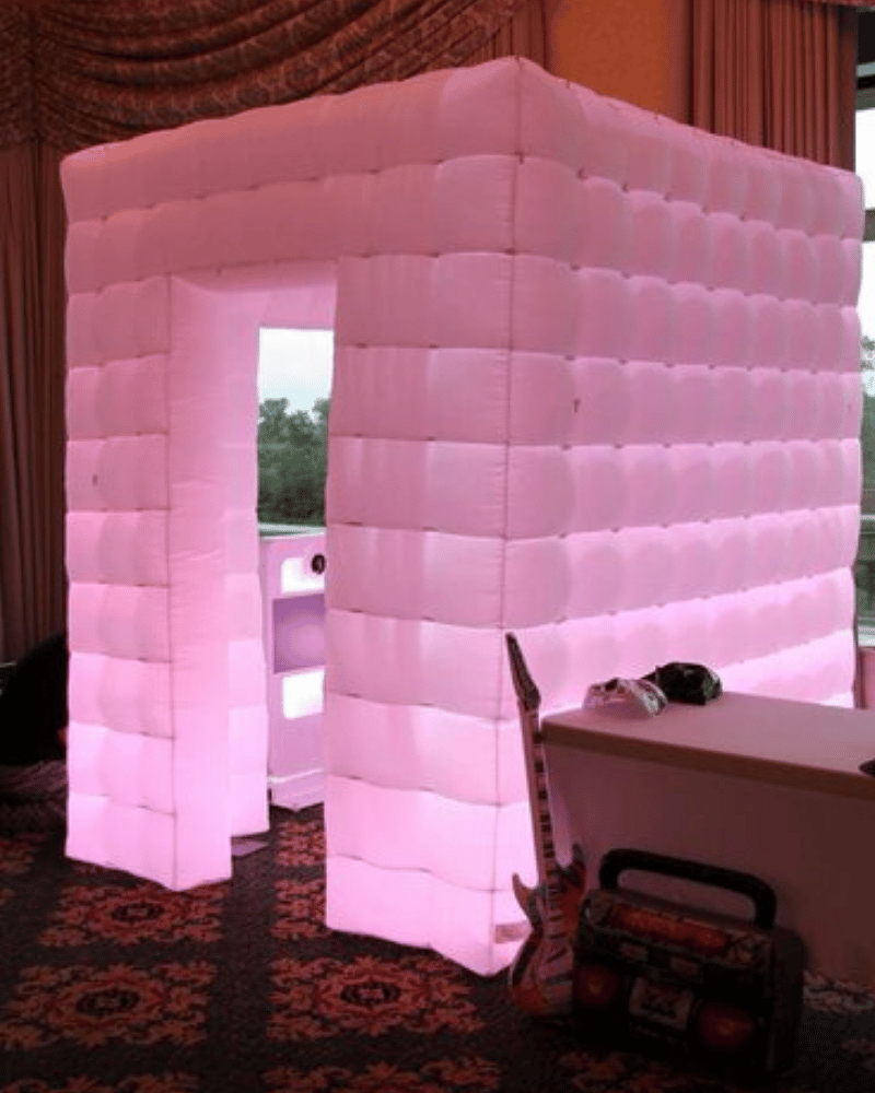 The inflatable photo booth, glowing with soft pink light, offers a unique and eye-catching backdrop for event photos.