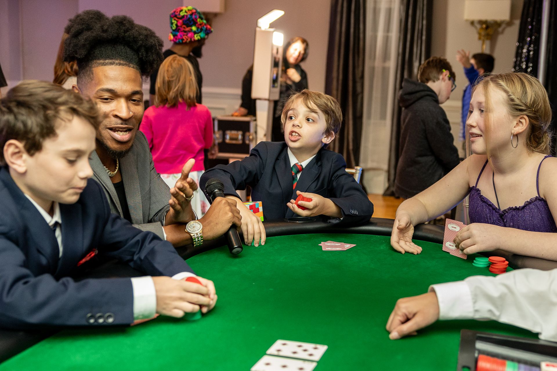A group of people sitting around a green card table, playing a game with chips and cards.