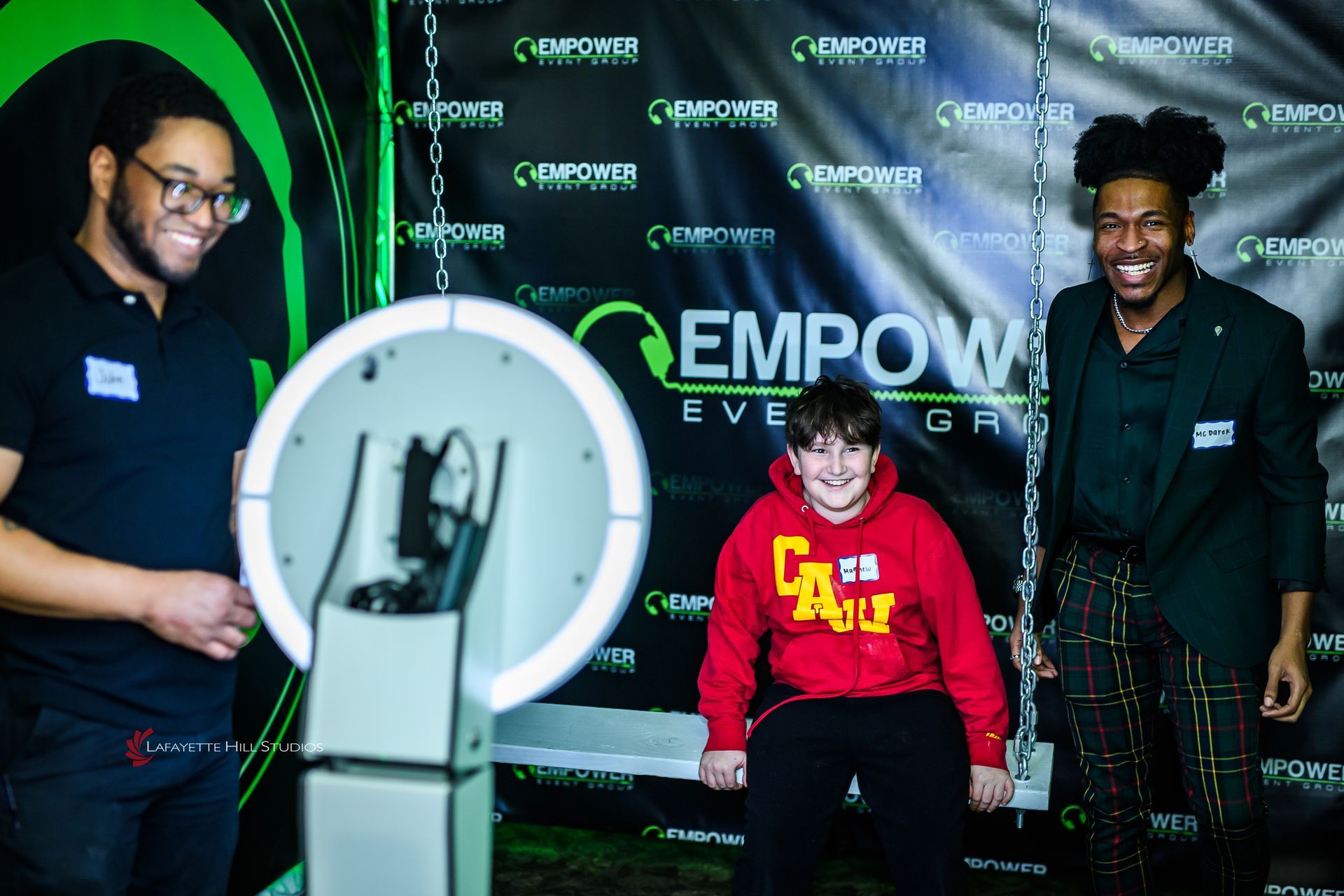 Professional Empower Event Group team members seated together, smiling confidently in front of branded backdrop, ready for event entertainment.