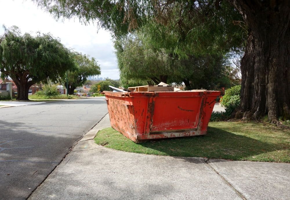 A red dumpster is sitting on the side of the road. — Bins on Rims in Macksville, NSW