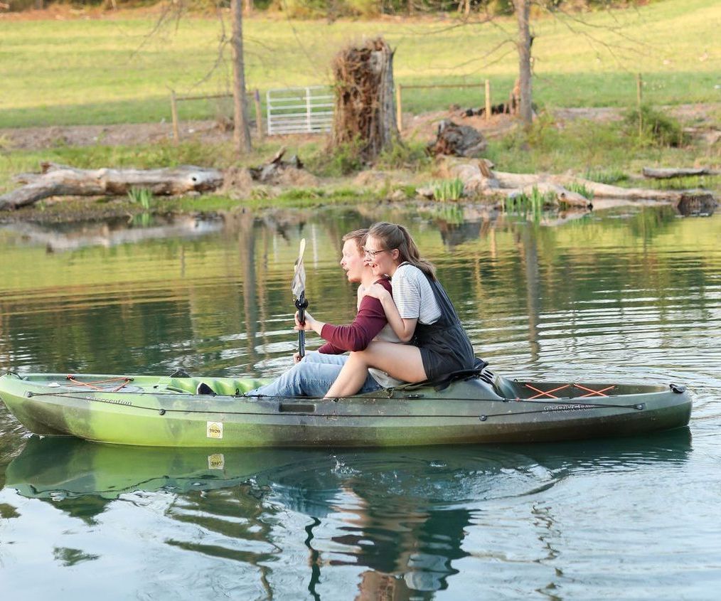 A man and a woman are sitting in a kayak on a lake.