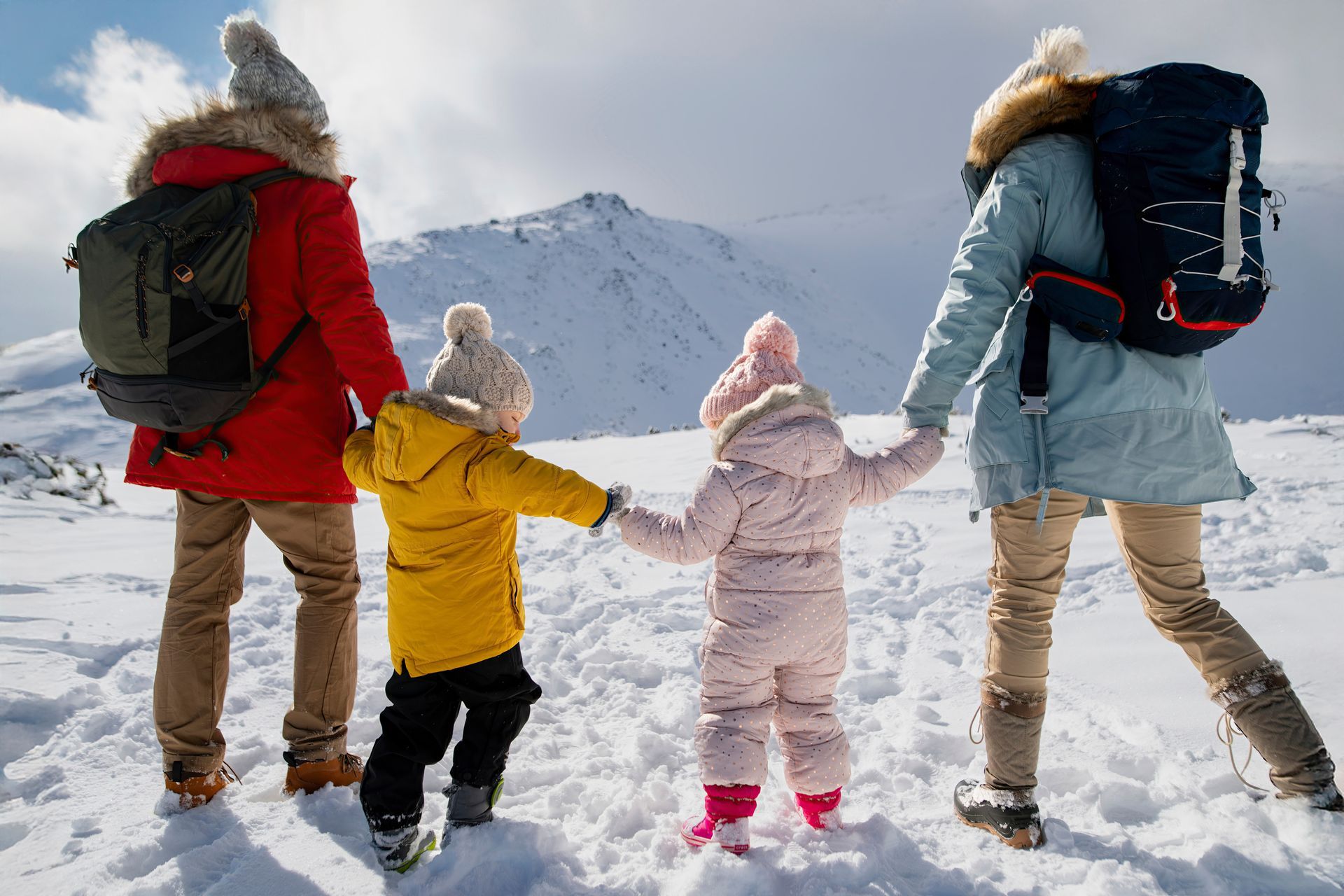 A family is standing in the snow holding hands.