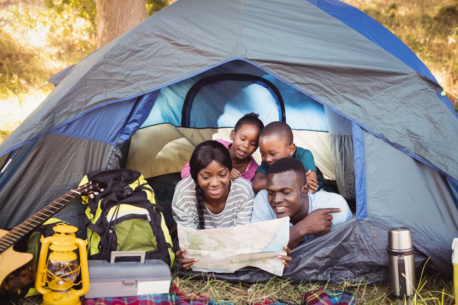 A family is laying in a tent looking at a map.