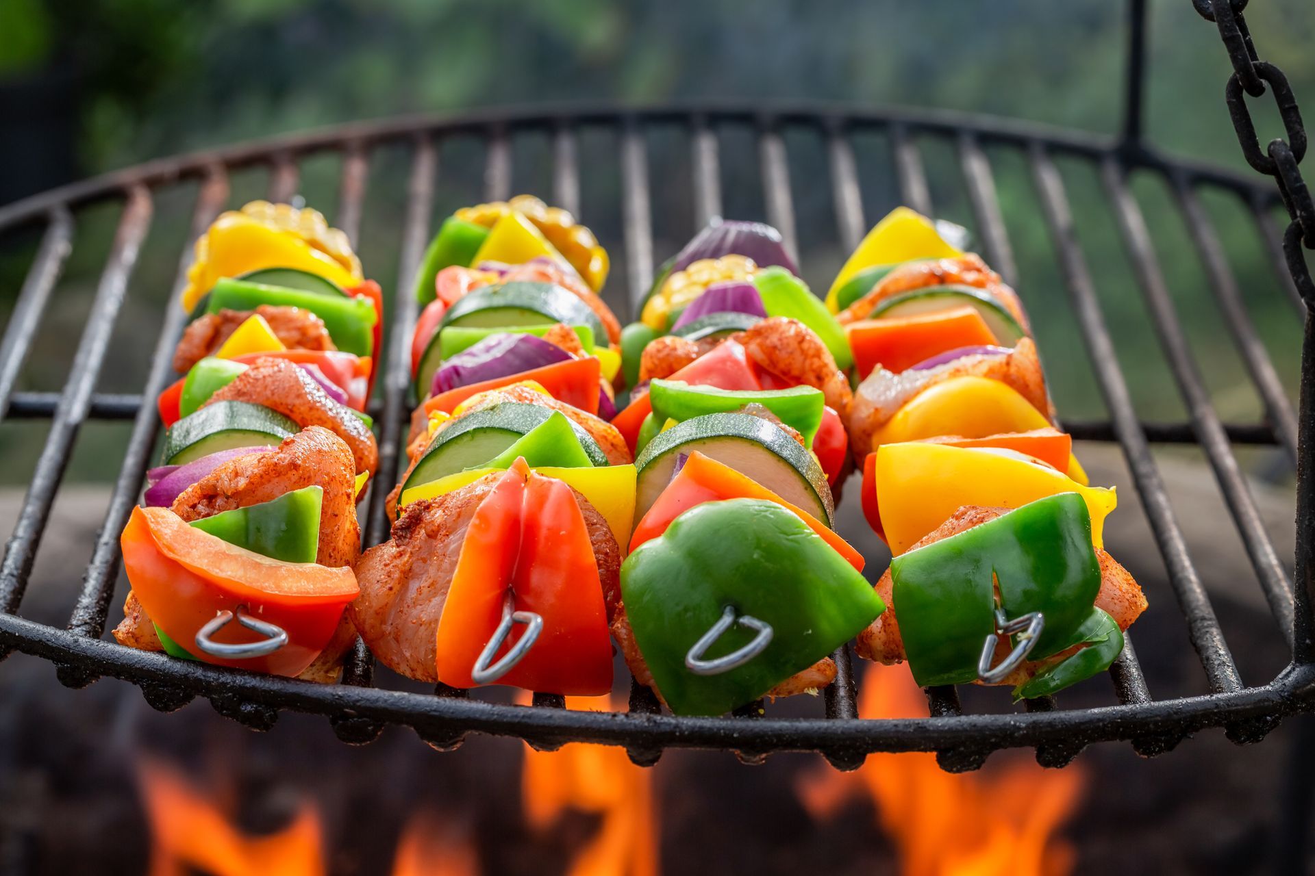 Kabobs with colorful vegetables and chicken grilling over an open flame.