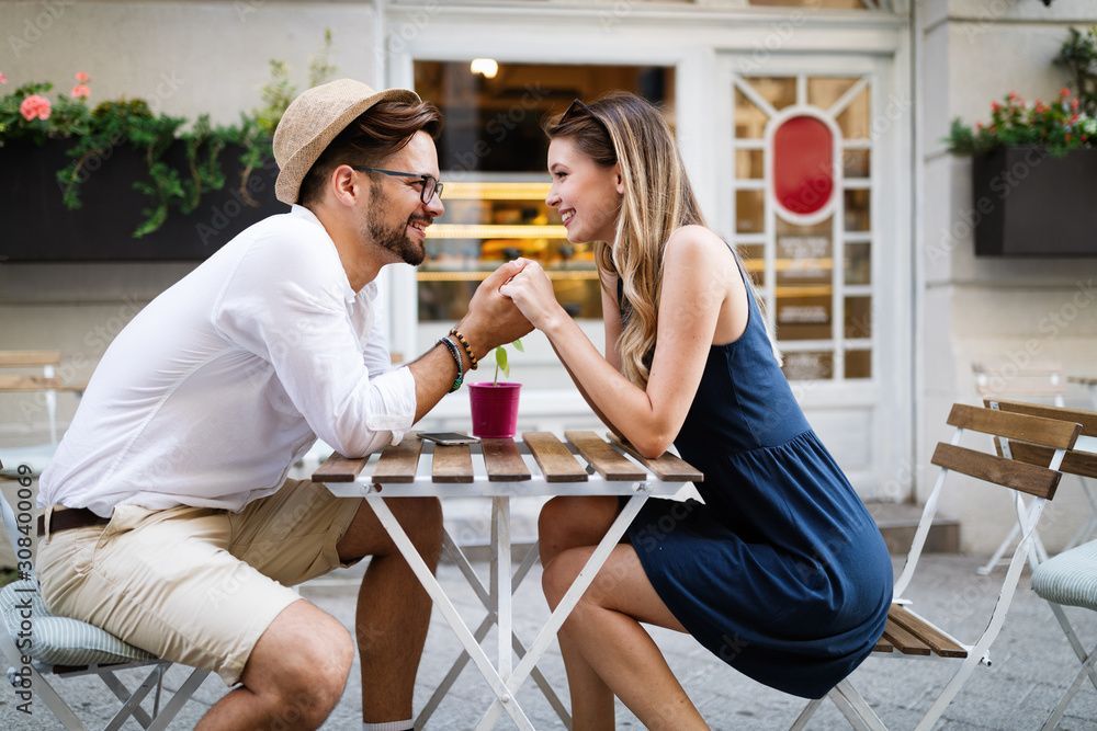 A man and a woman are sitting at a table holding hands.