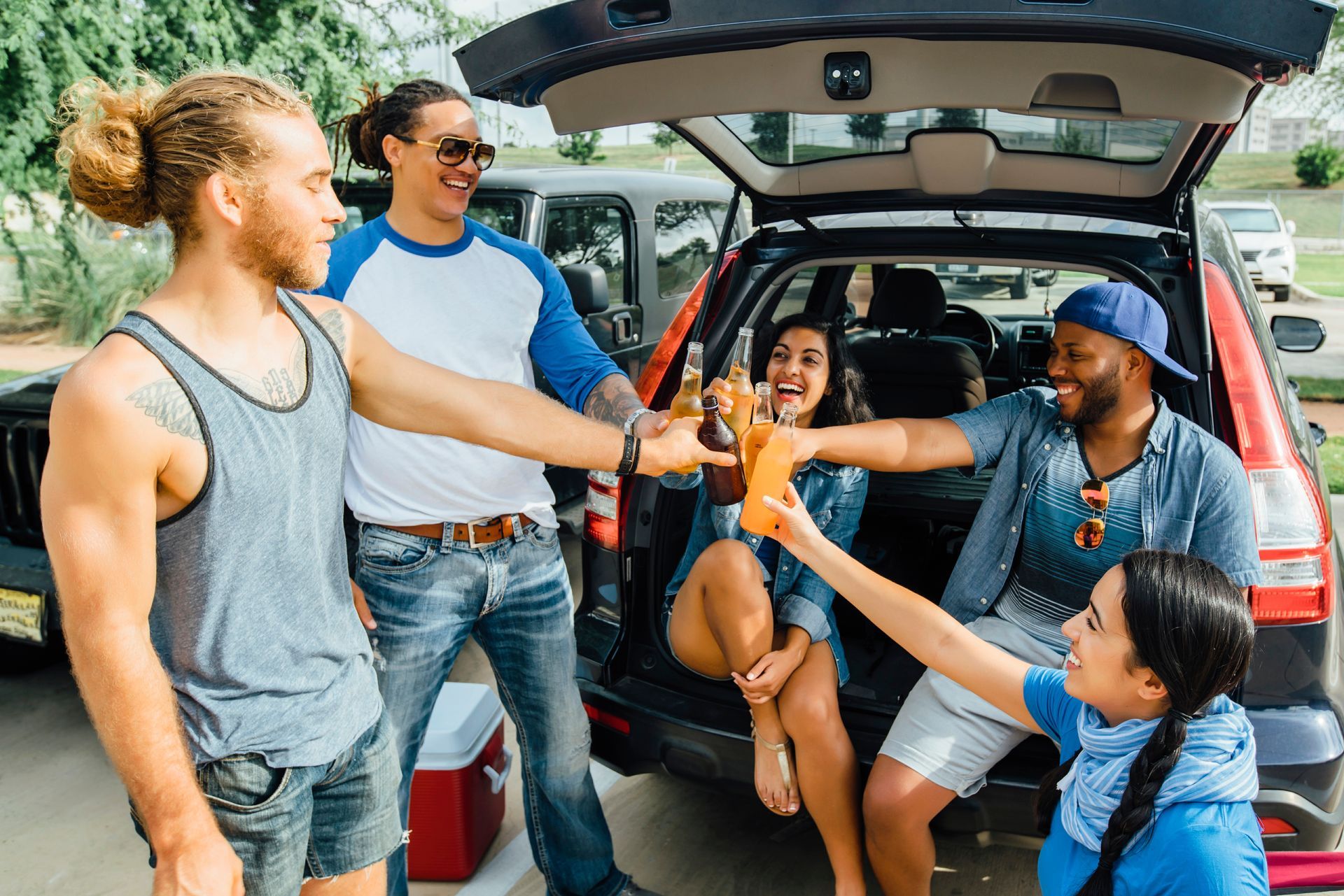 A group of people are toasting in the back of a car.