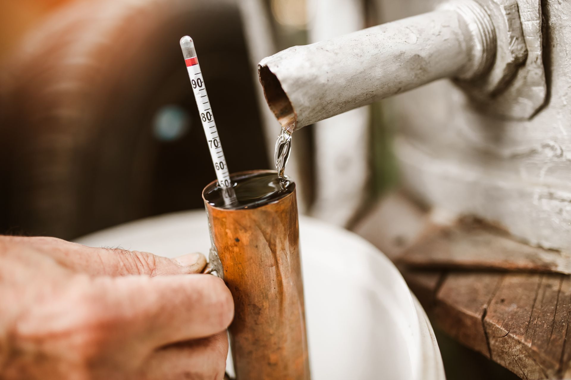 A person is pouring liquid into a glass with a thermometer.