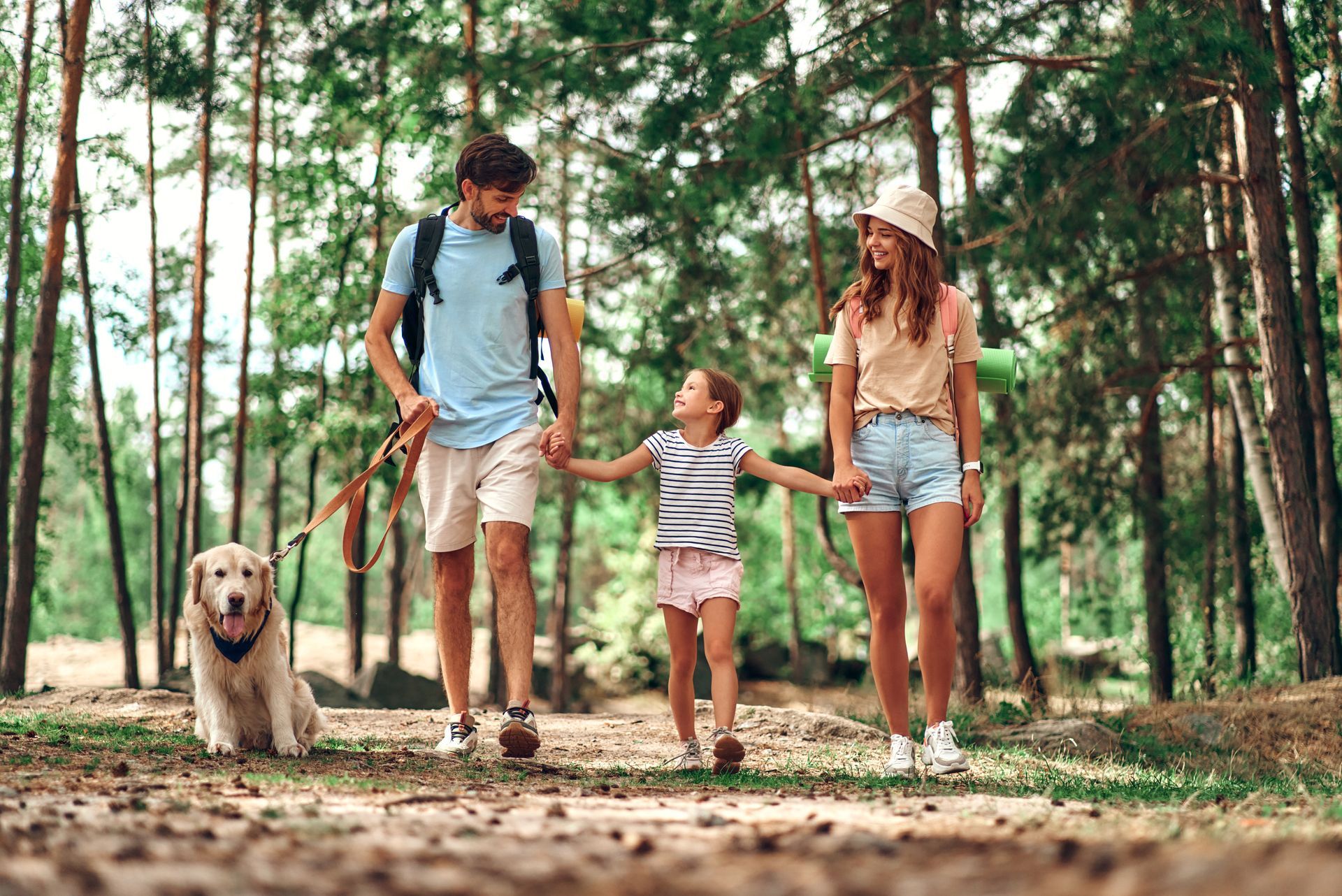 A family is walking their dog in the woods.
