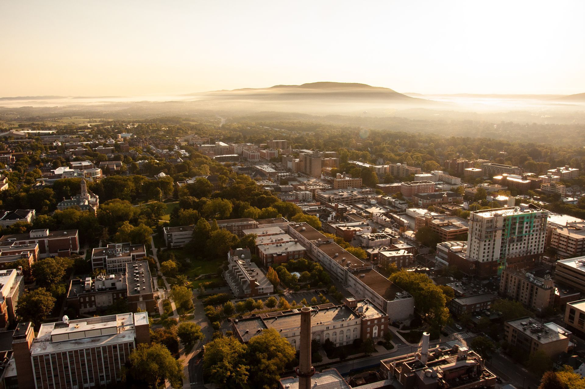 An aerial view of State College, PA at sunset with a mountain in the background.