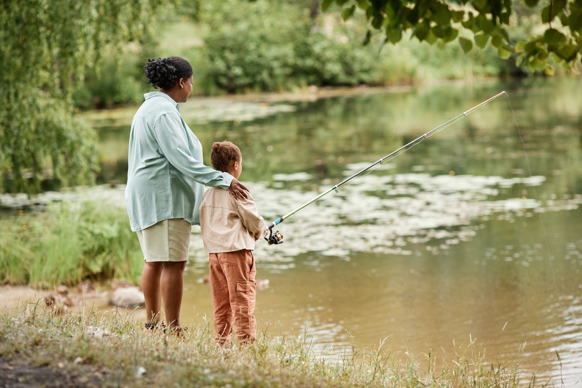 A woman and a child are fishing in a lake.