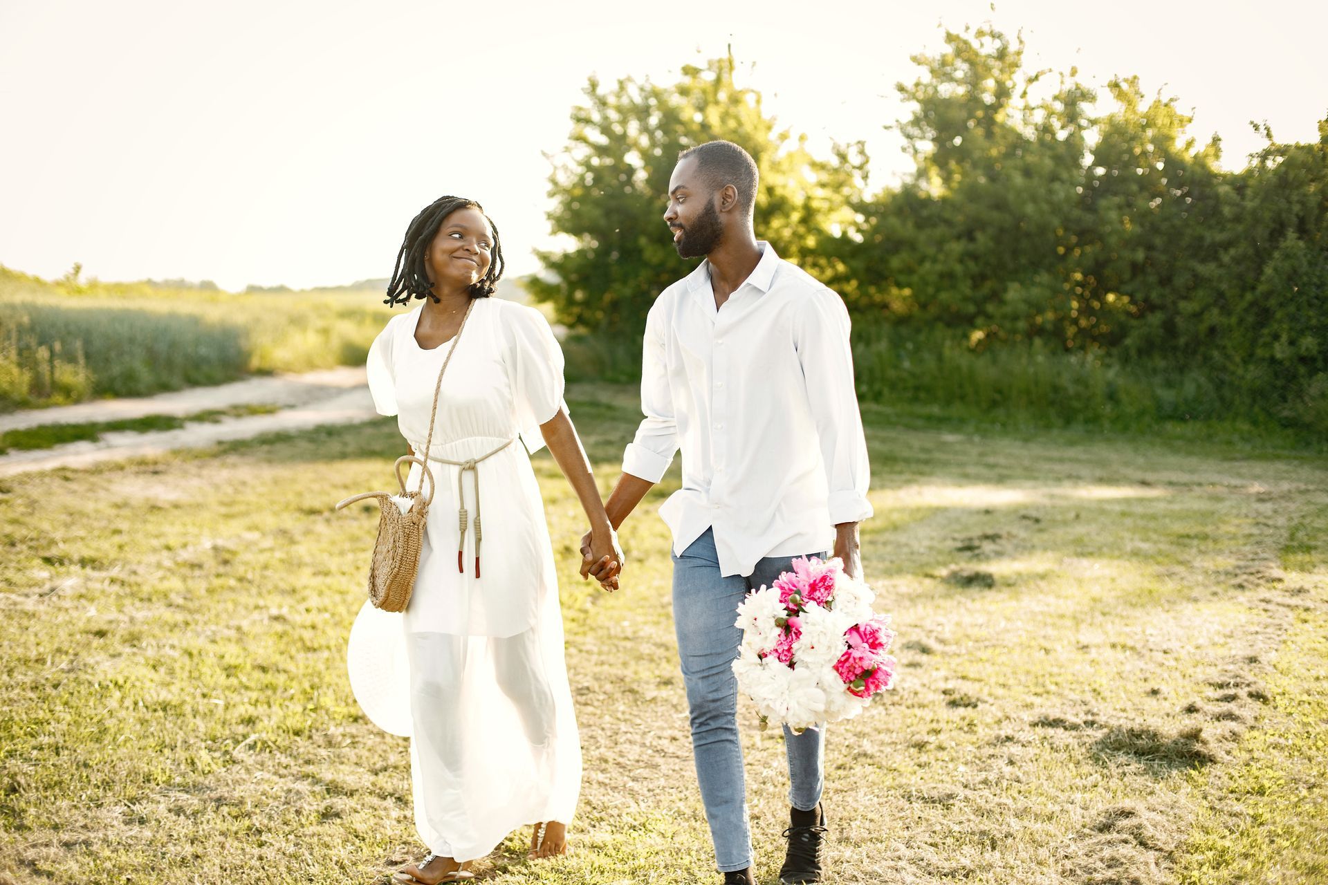 A man and a woman are holding hands while walking in a field.