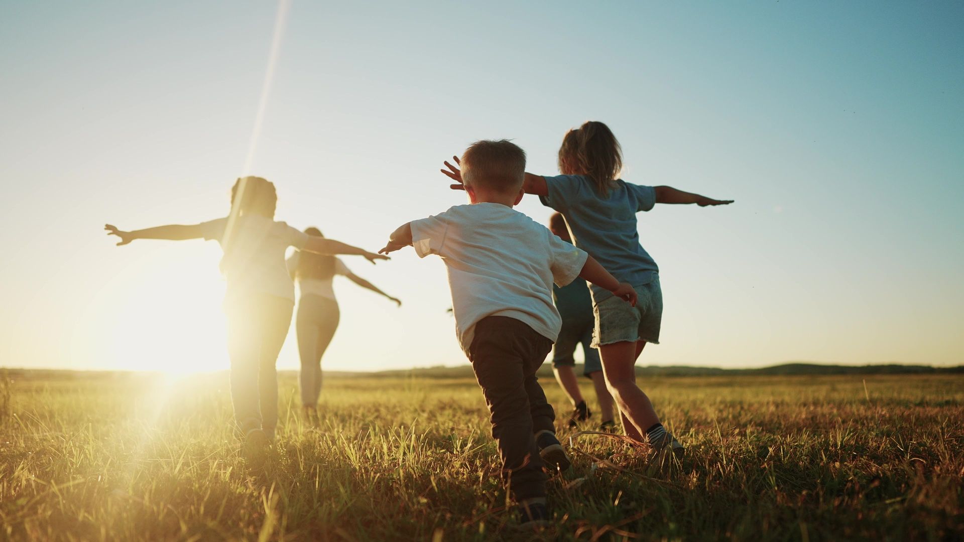 A group of children are playing in a field at sunset.