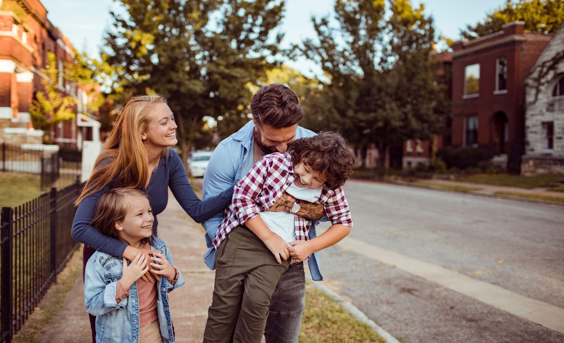 A family is walking down a sidewalk in a residential neighborhood.