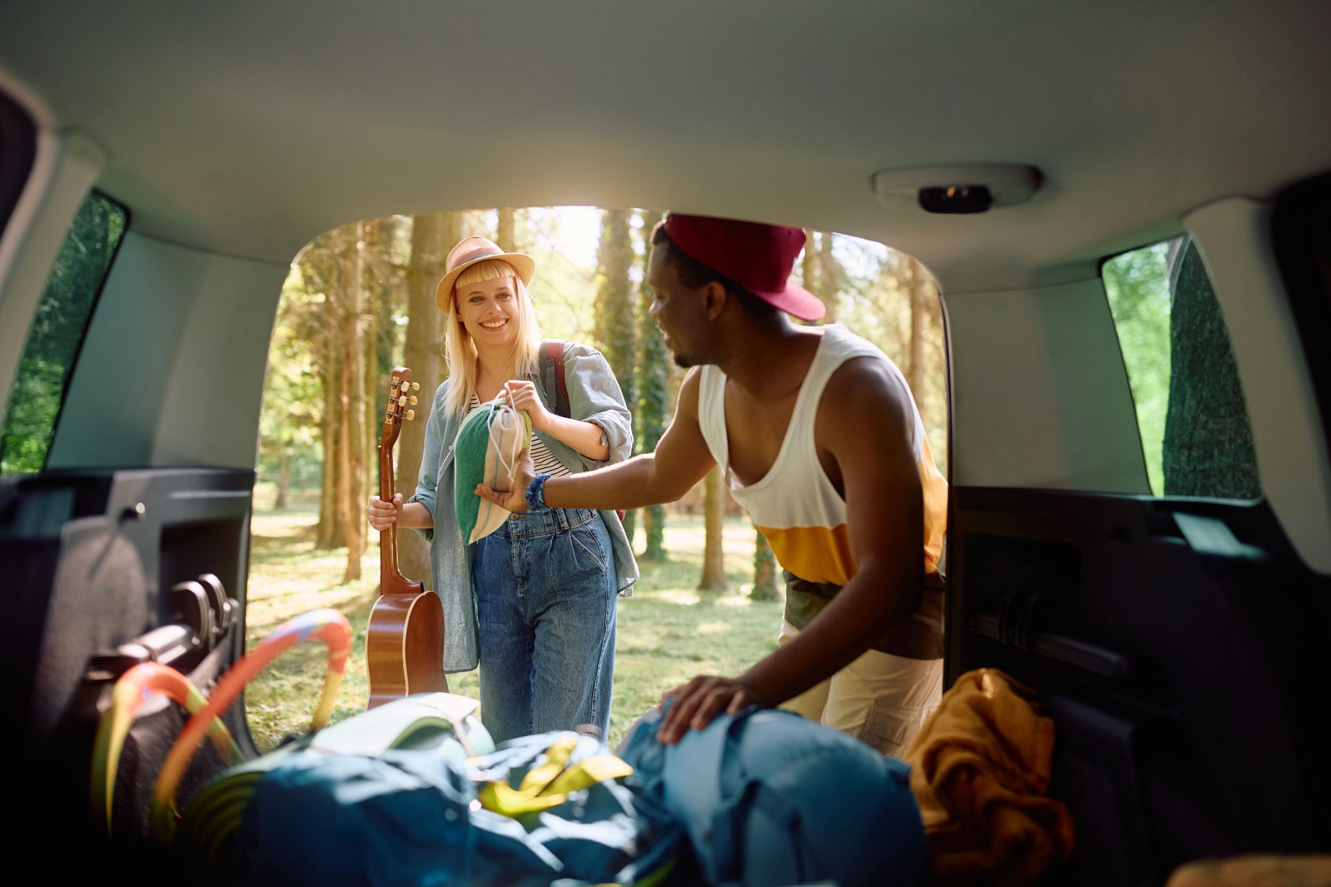 A man and a woman are standing in the back of a car.