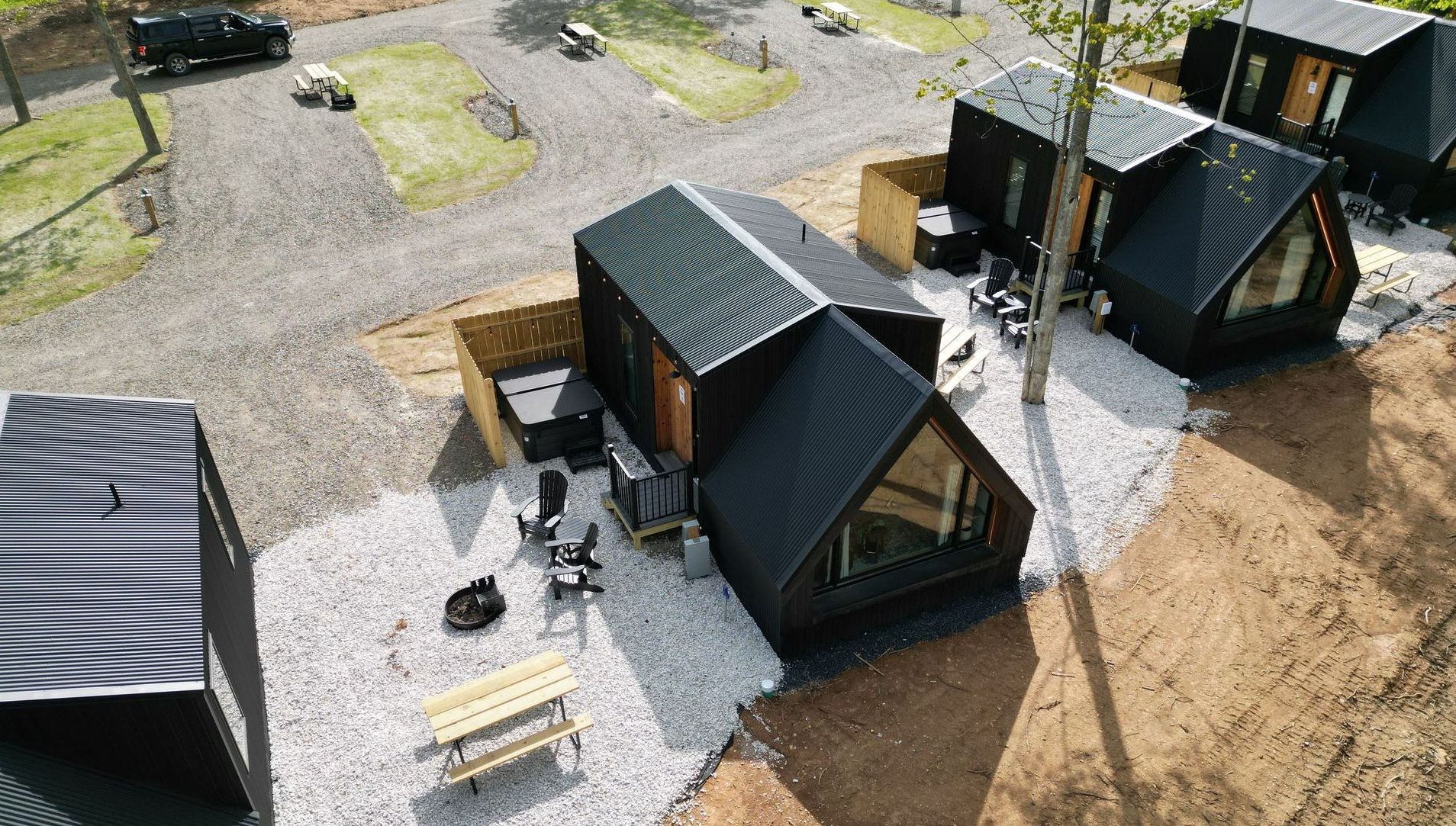 An aerial view of a row of small black glamping houses.