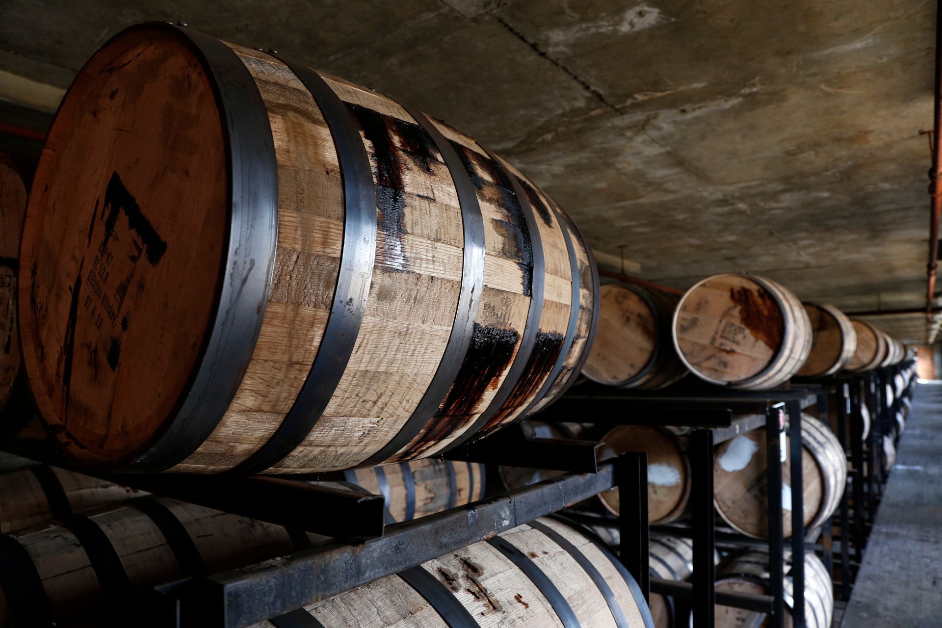 A row of wooden barrels stacked on top of each other in a warehouse.