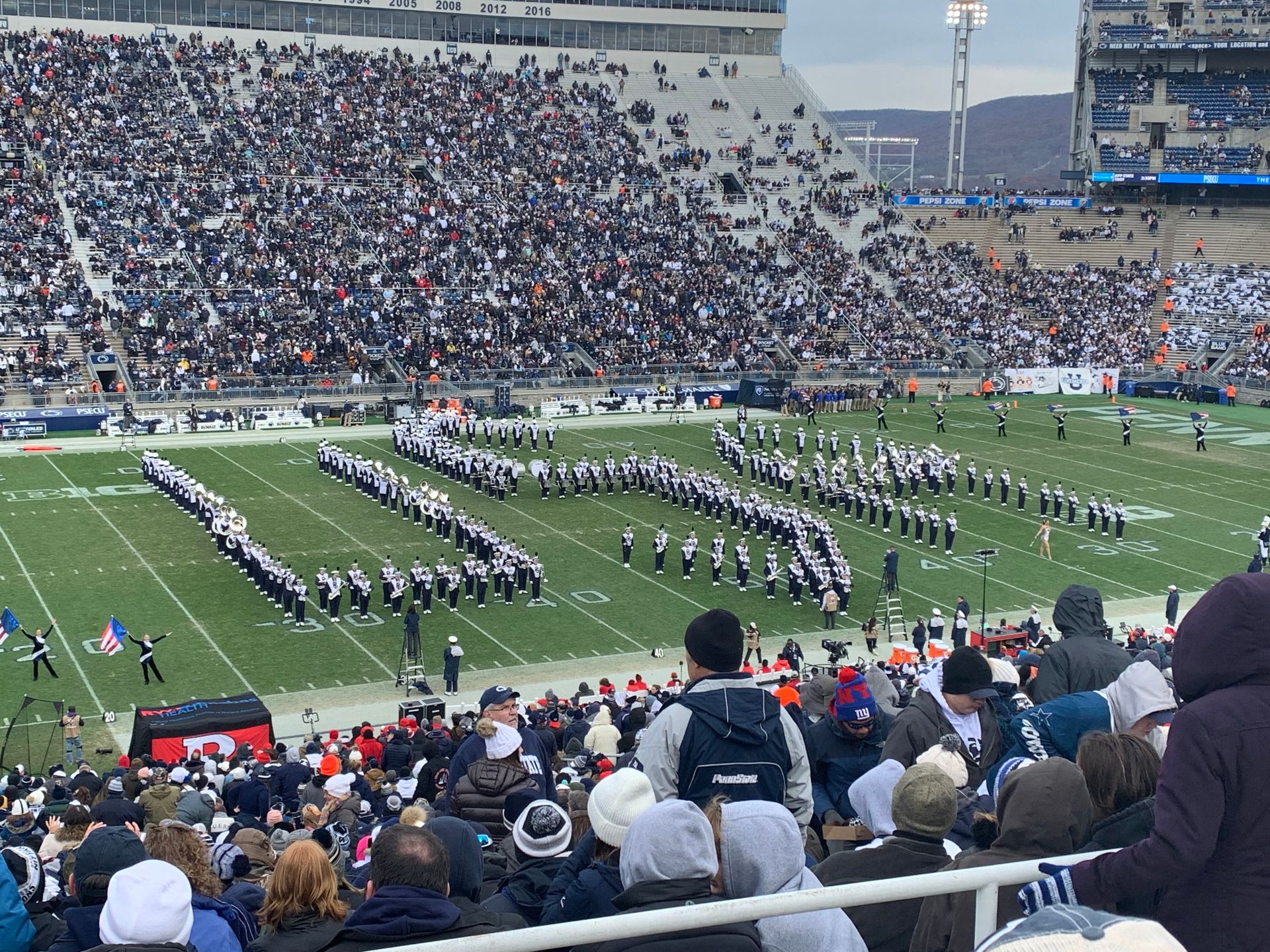 A marching band is performing on the field at a football game