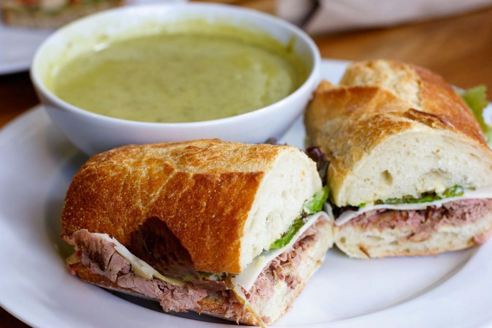 A sandwich and a bowl of soup are on a white plate.