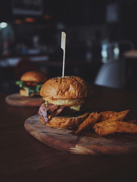 A hamburger and french fries on a wooden cutting board.