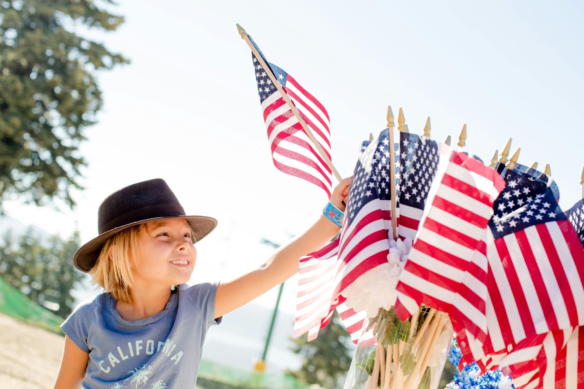 A young boy in a hat is touching an american flag.