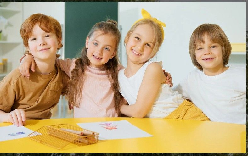 Two children sit back-to-back on a tree swing, enjoying the sunset over a hilly landscape.