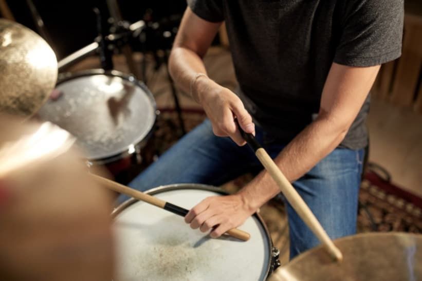 Person playing drums with drumsticks; close-up.