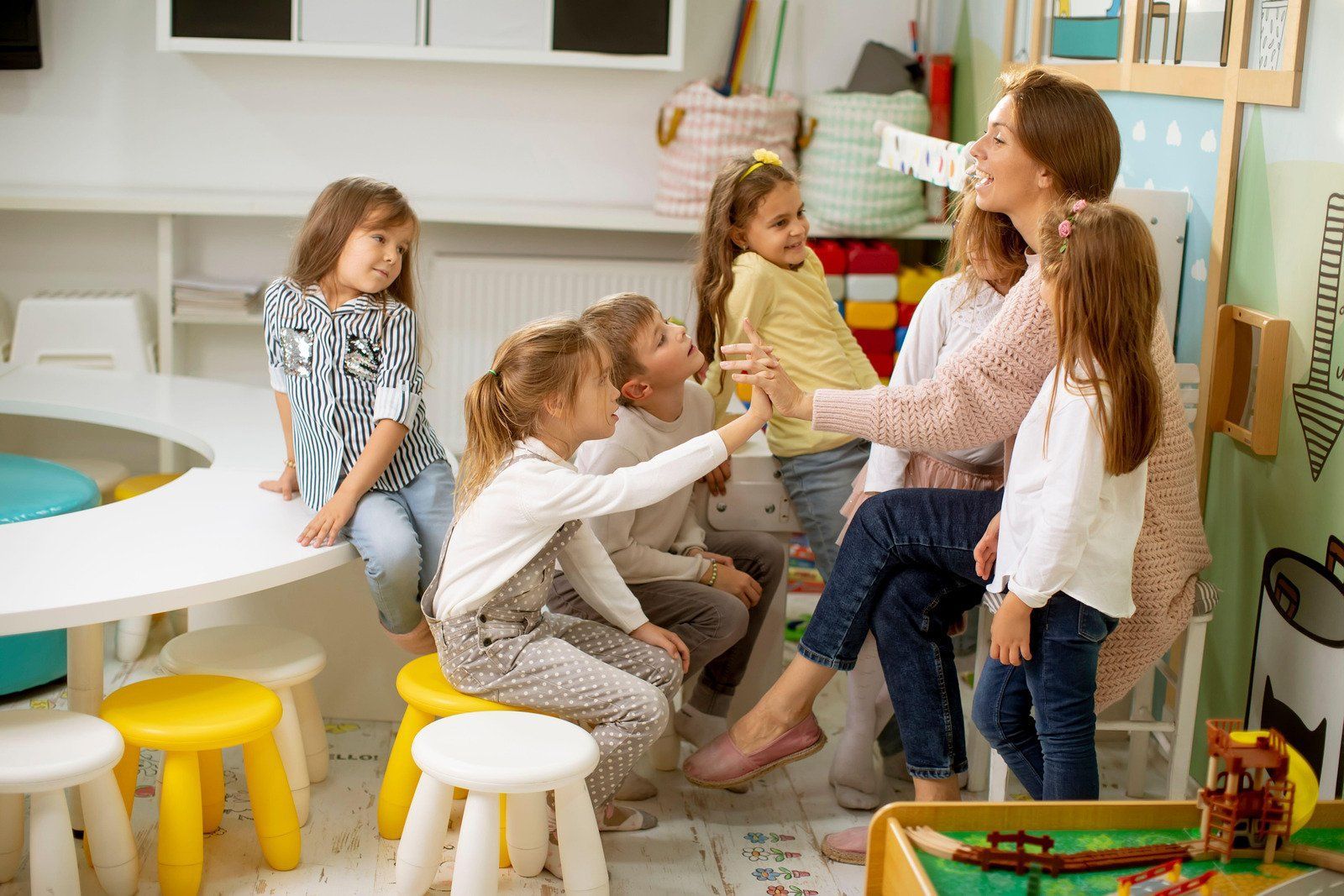 Teacher with young children in a classroom; they are interacting and smiling.
