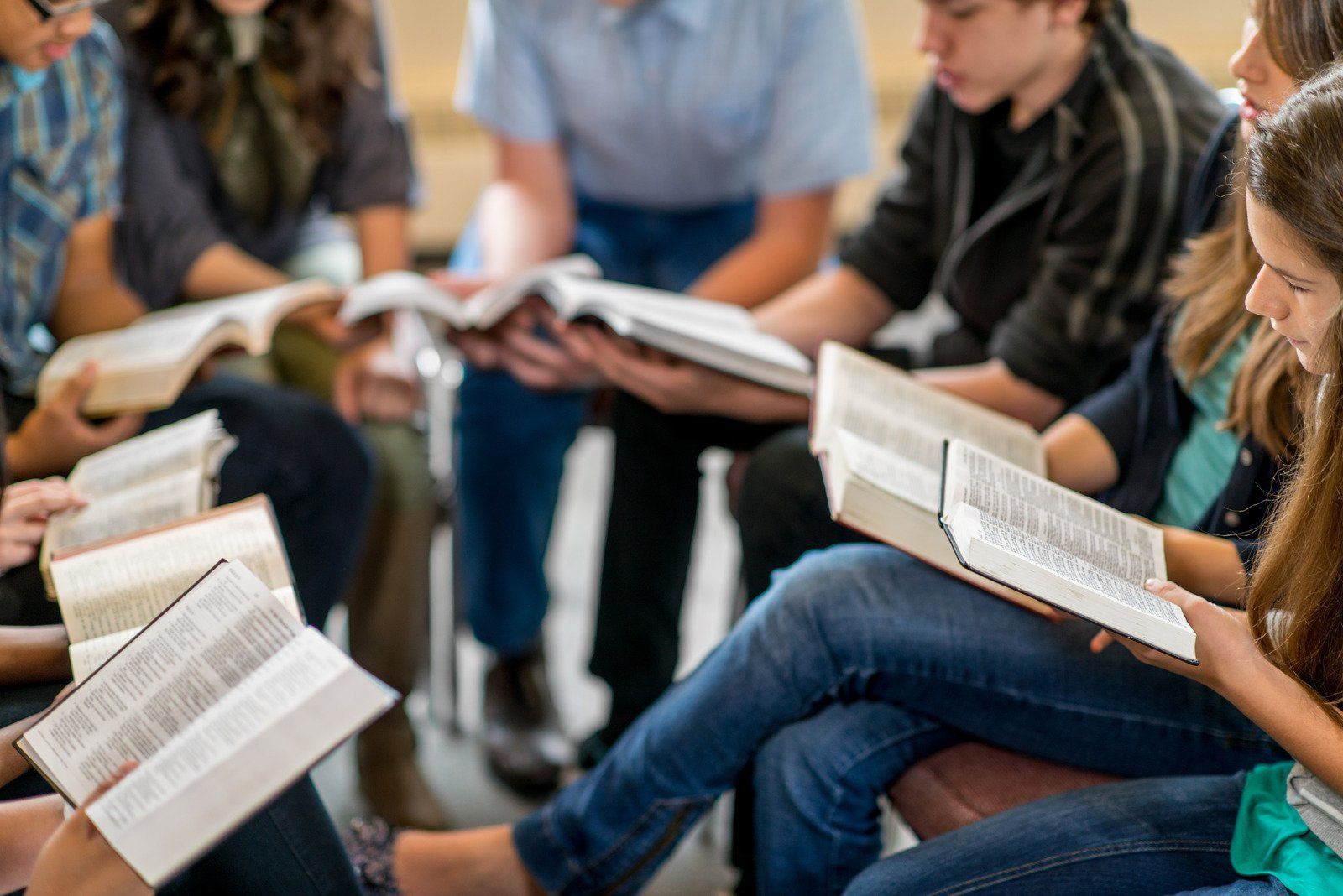 Group of young people sitting in a circle, reading books together.