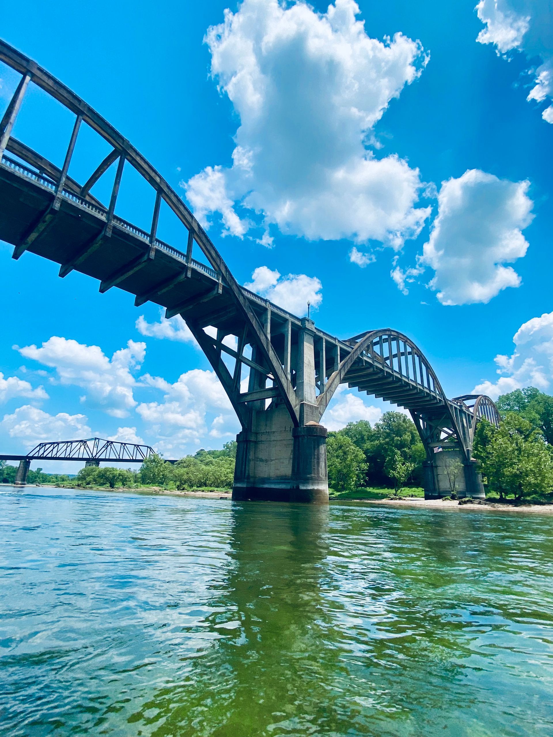 A bridge over a river with a blue sky and clouds