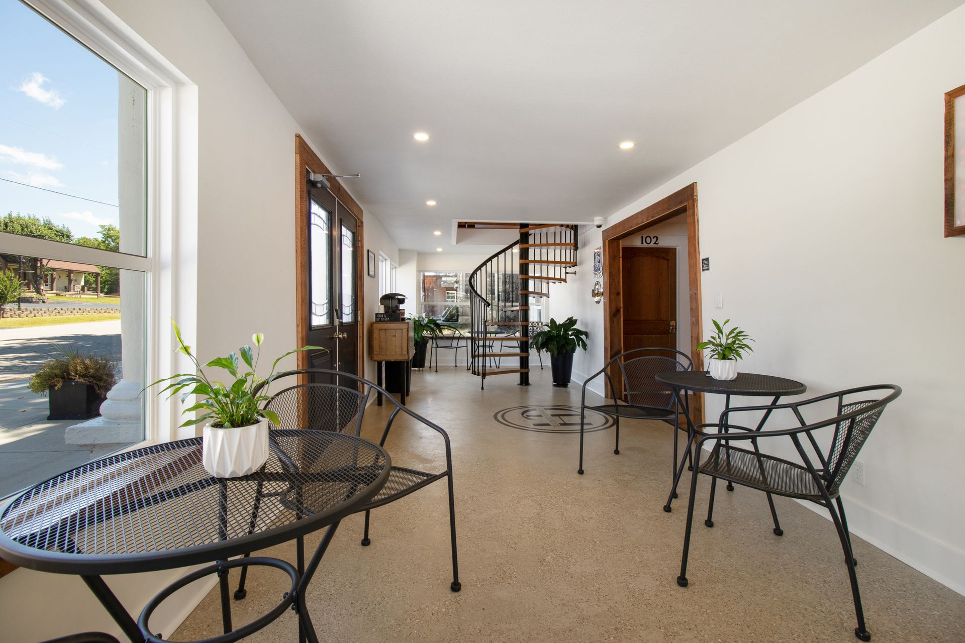 A living room with a table and chairs and a spiral staircase.