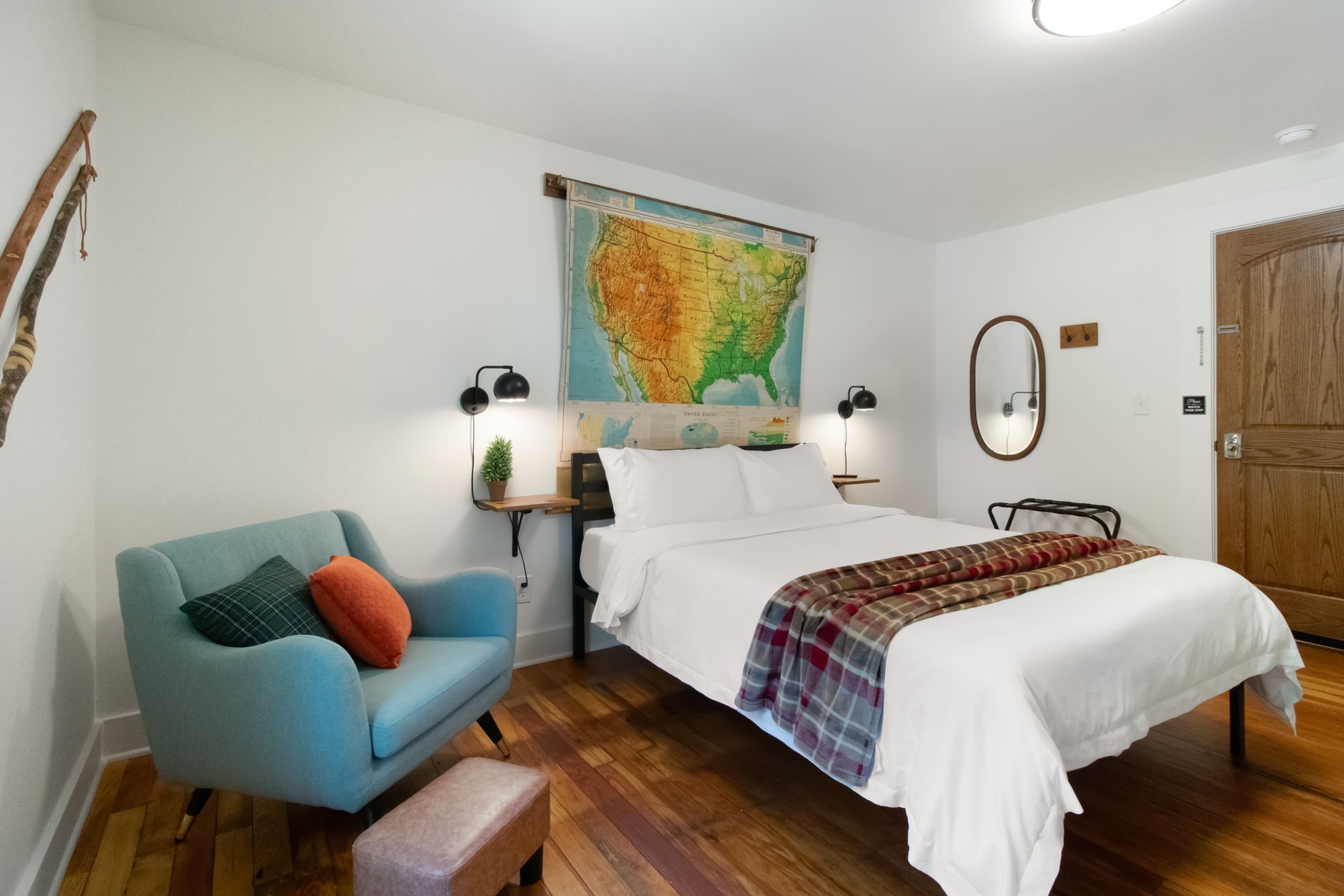A bedroom with a bed a chair and a map on the wall