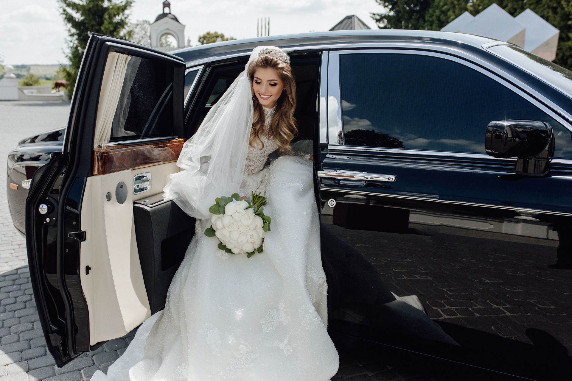 Bride in a white gown exits a black car