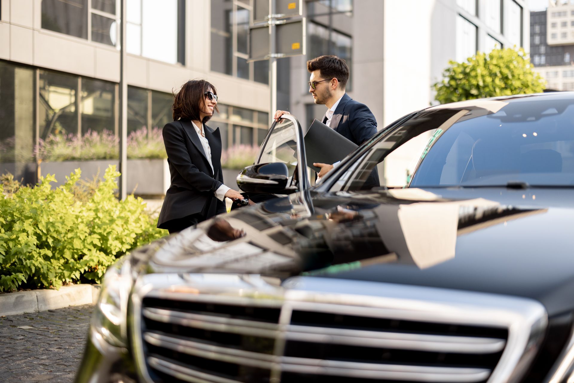 Businesspeople near a black car