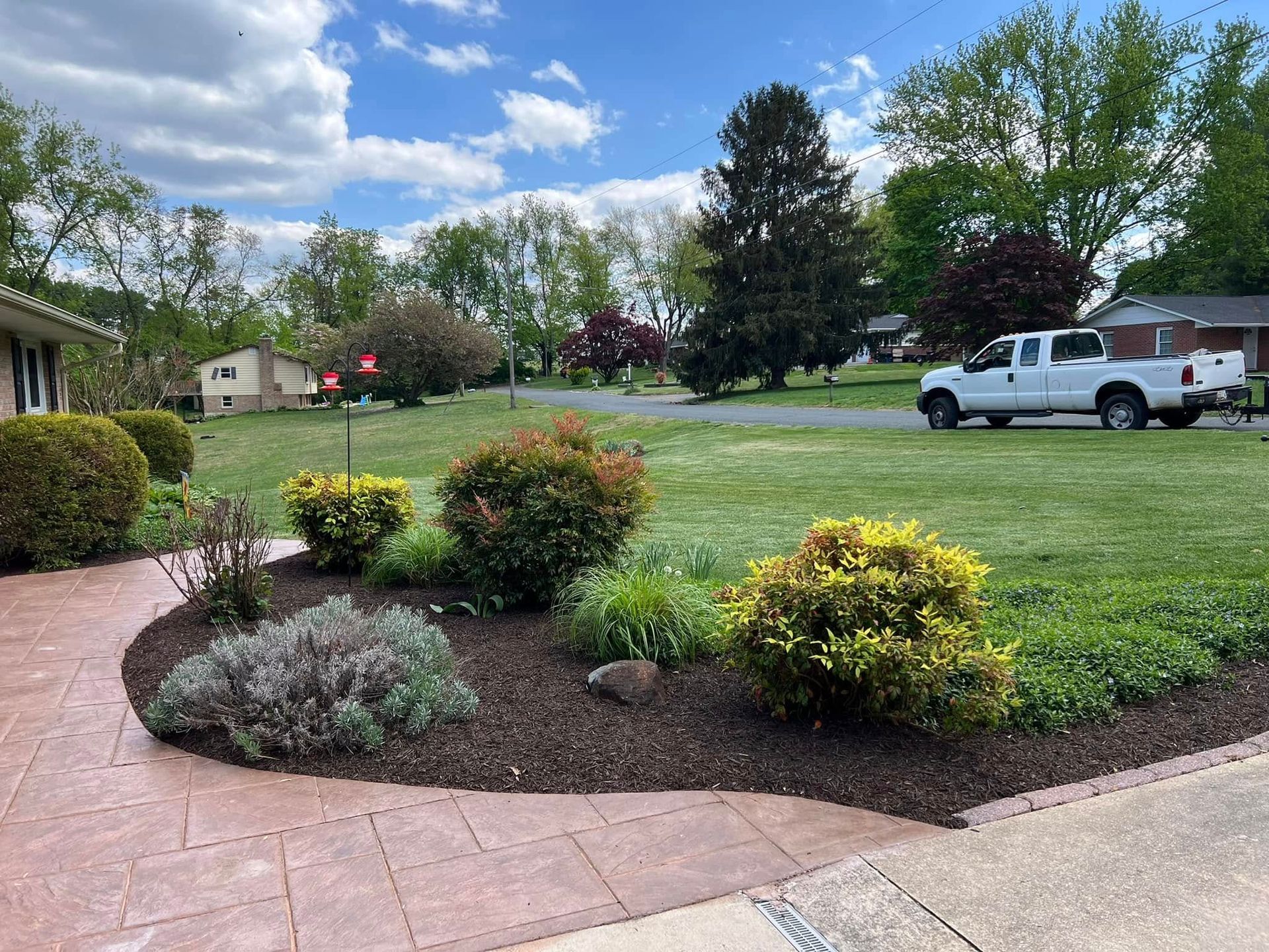A white truck is parked in front of a lush green yard.