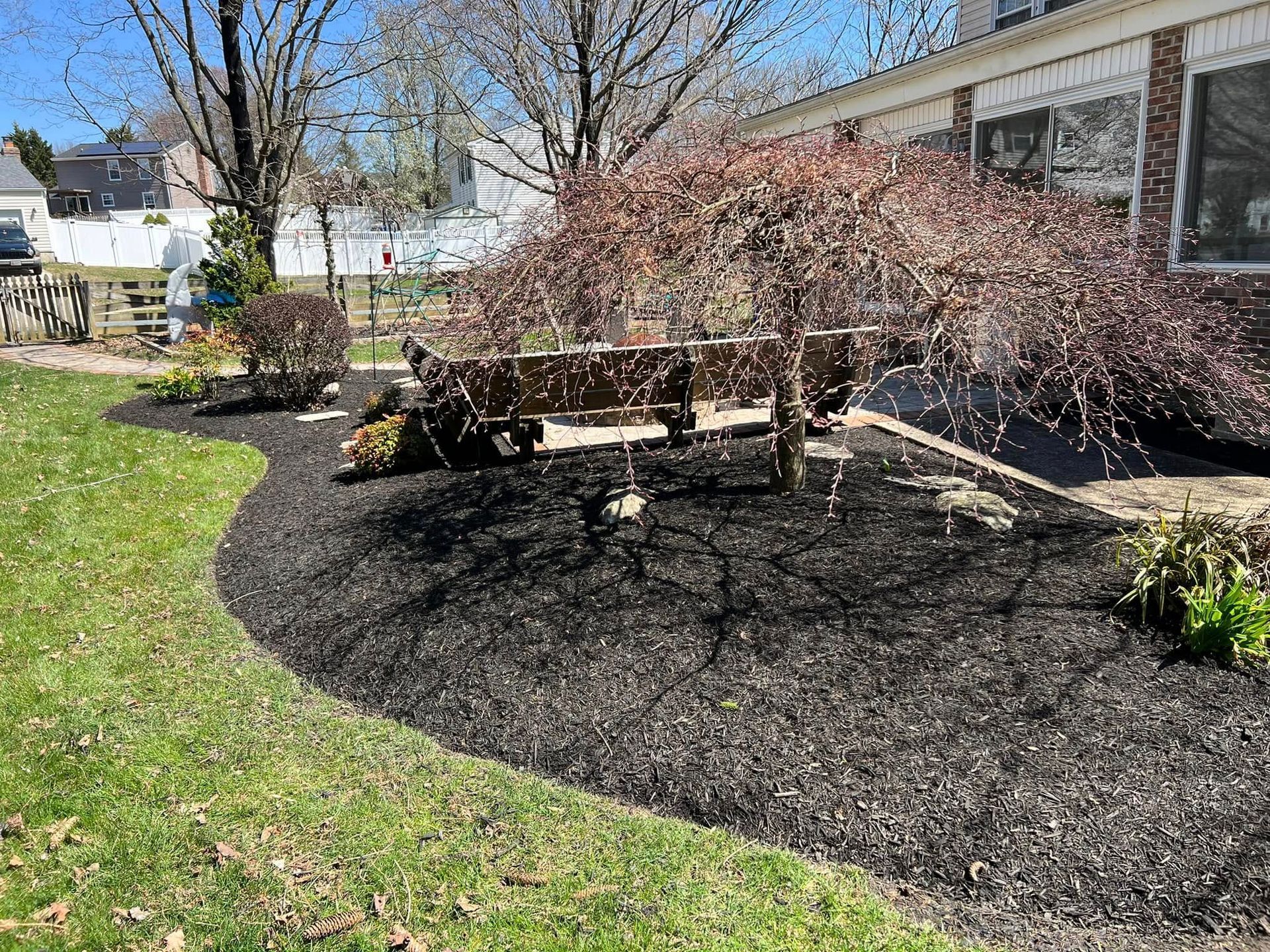 A park bench is sitting in the middle of a lush green yard.