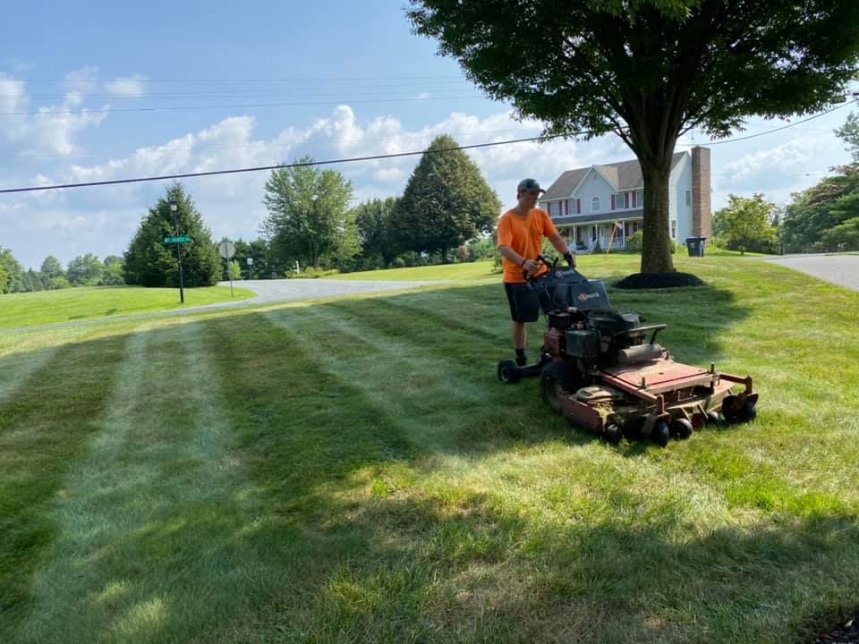 A man is mowing a lush green lawn with a lawn mower.