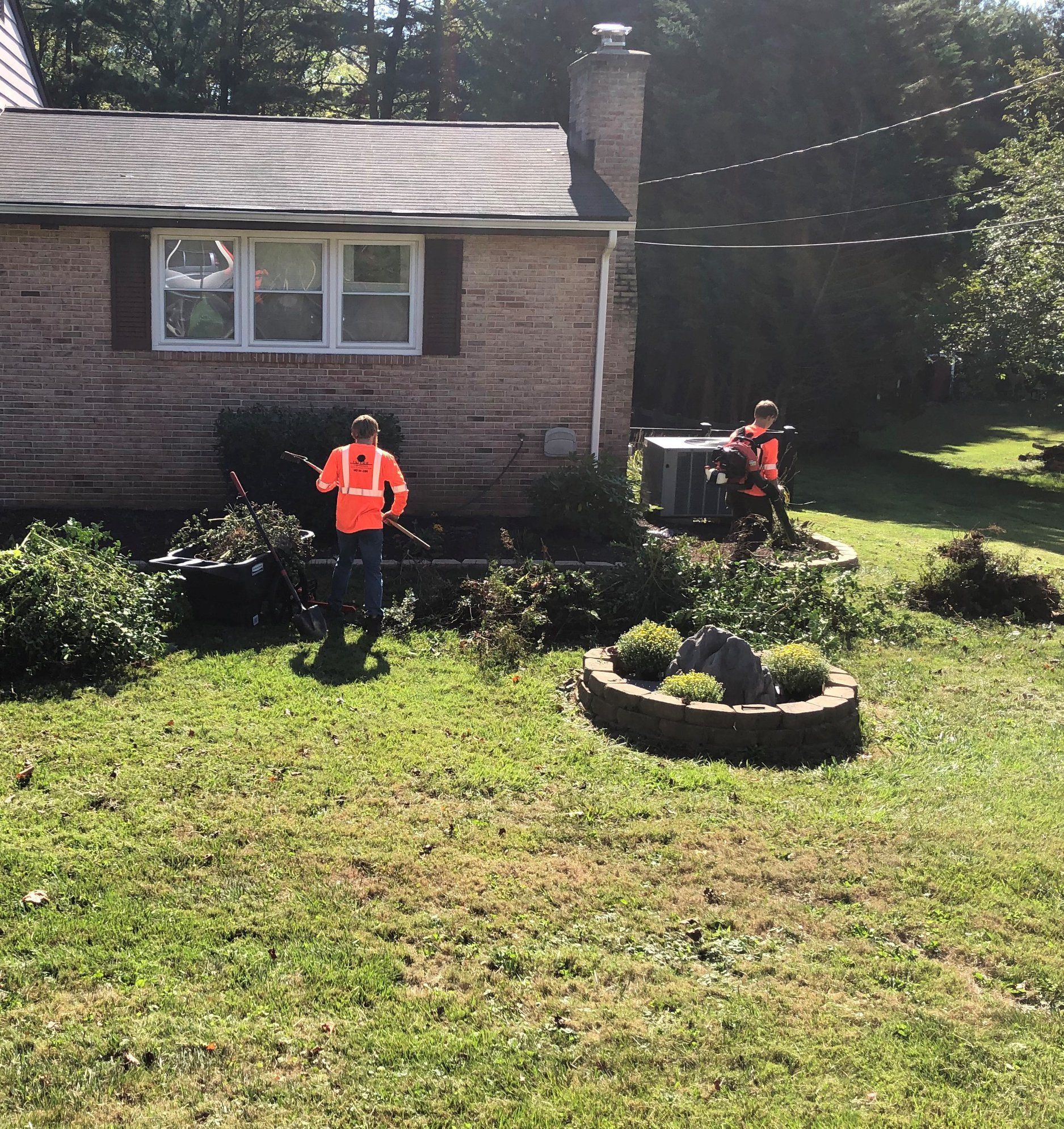 A man in an orange vest is standing in front of a house
