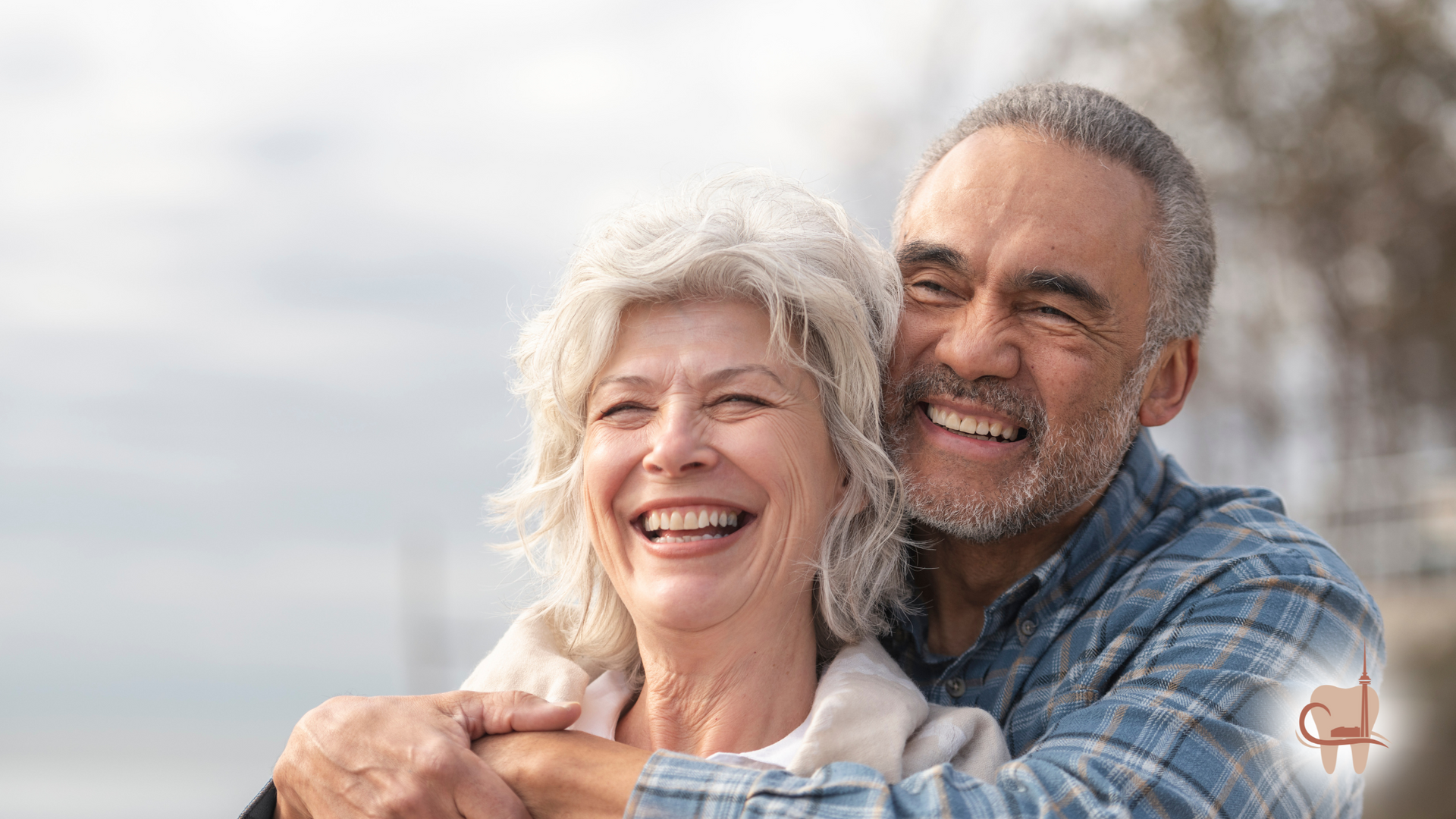 Smiling elderly couple embracing outdoors. Man with beard hugs woman with gray hair.