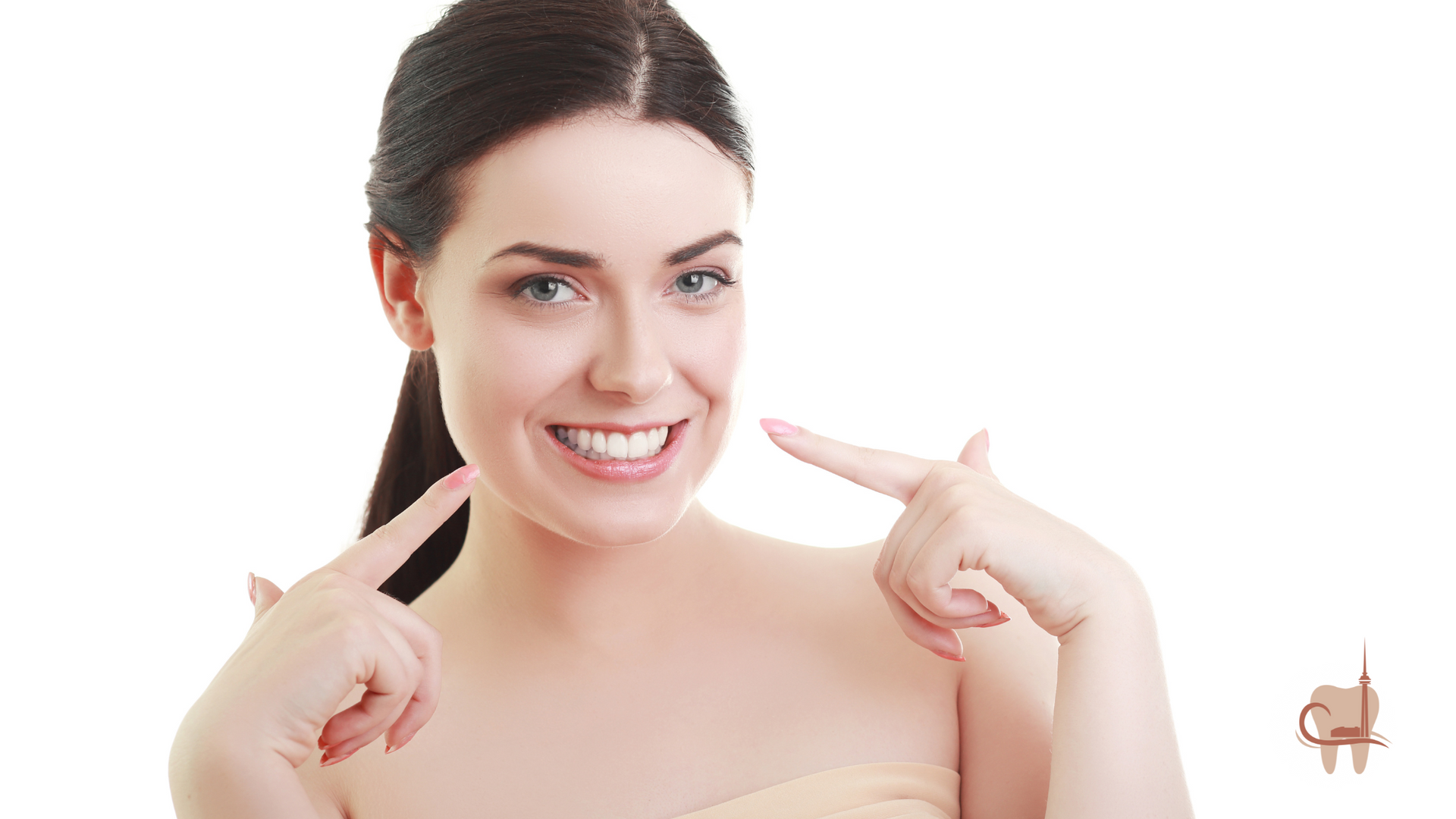 Woman with dark hair smiles, pointing at her teeth.