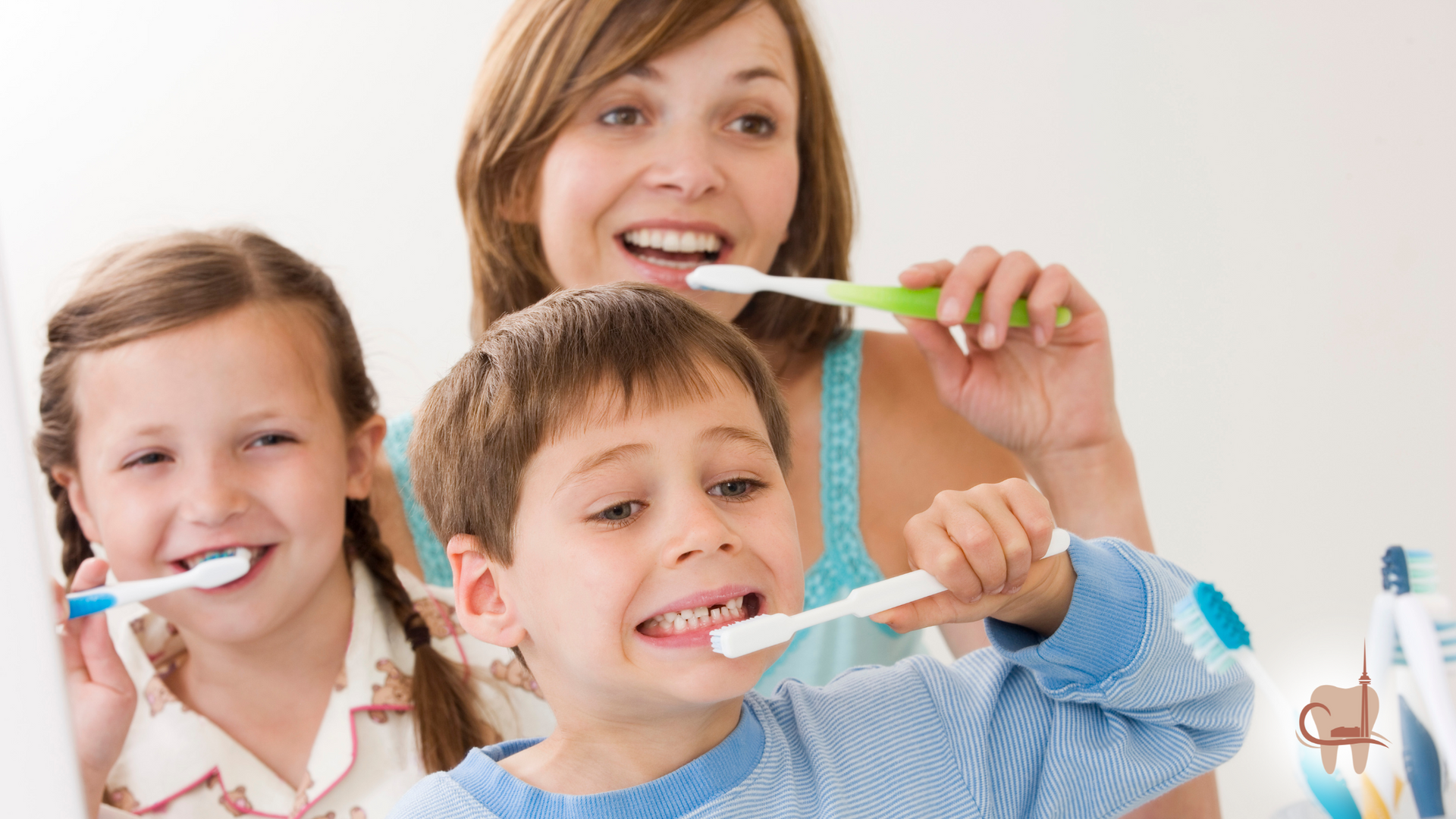 Family brushing teeth together in bathroom. Mother, daughter, and son smiling, holding toothbrushes.