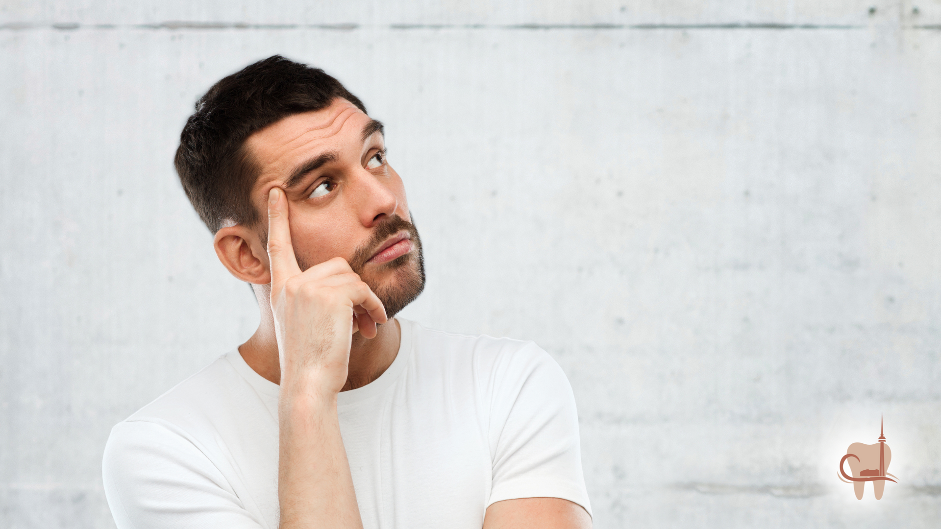 Man in white shirt with thoughtful expression, finger to temple, looking up. Gray background.
